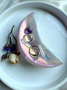Shimmery Aura Rose Quartz bowl in crescent moon shape, displayed with a ring and mini crystal carvings and clear quartz points