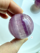 polished Candy Fluorite sphere with bold purple striping and soft translucent glow for spiritual clarity