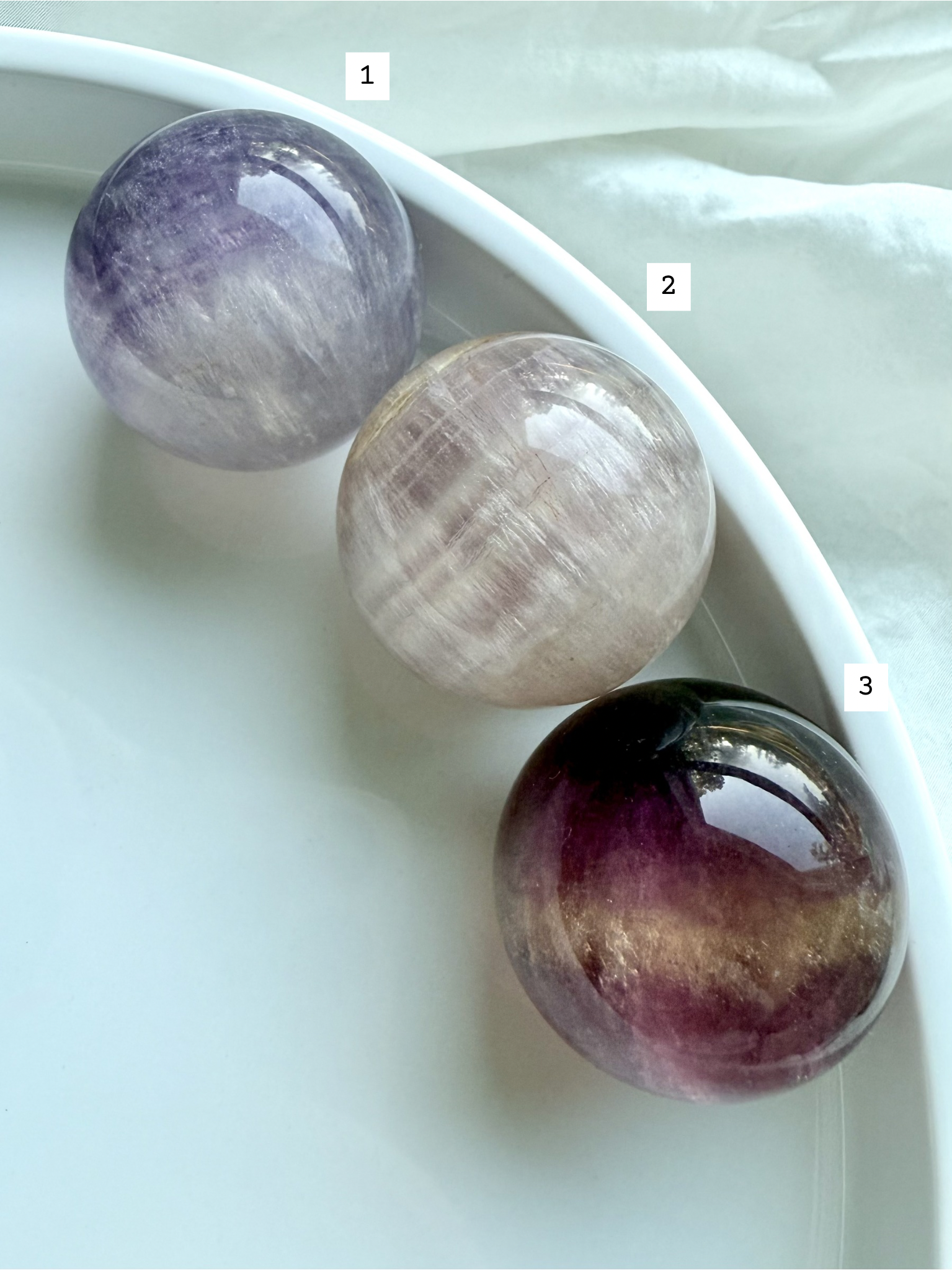 rare pink and purple Candy Fluorite spheres with silky layered patterns displayed on white dish