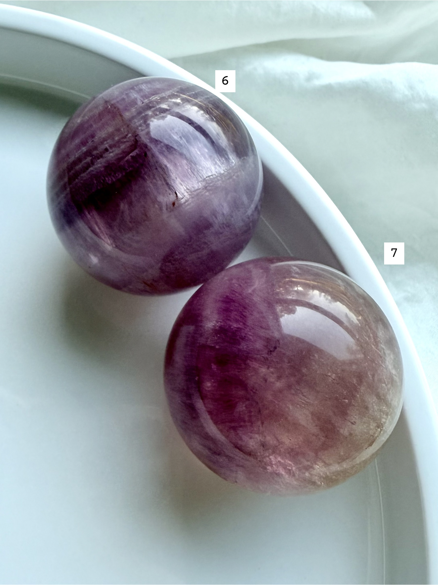 pair of polished Candy Fluorite spheres with silky magenta banding and luminous translucent crystal layers