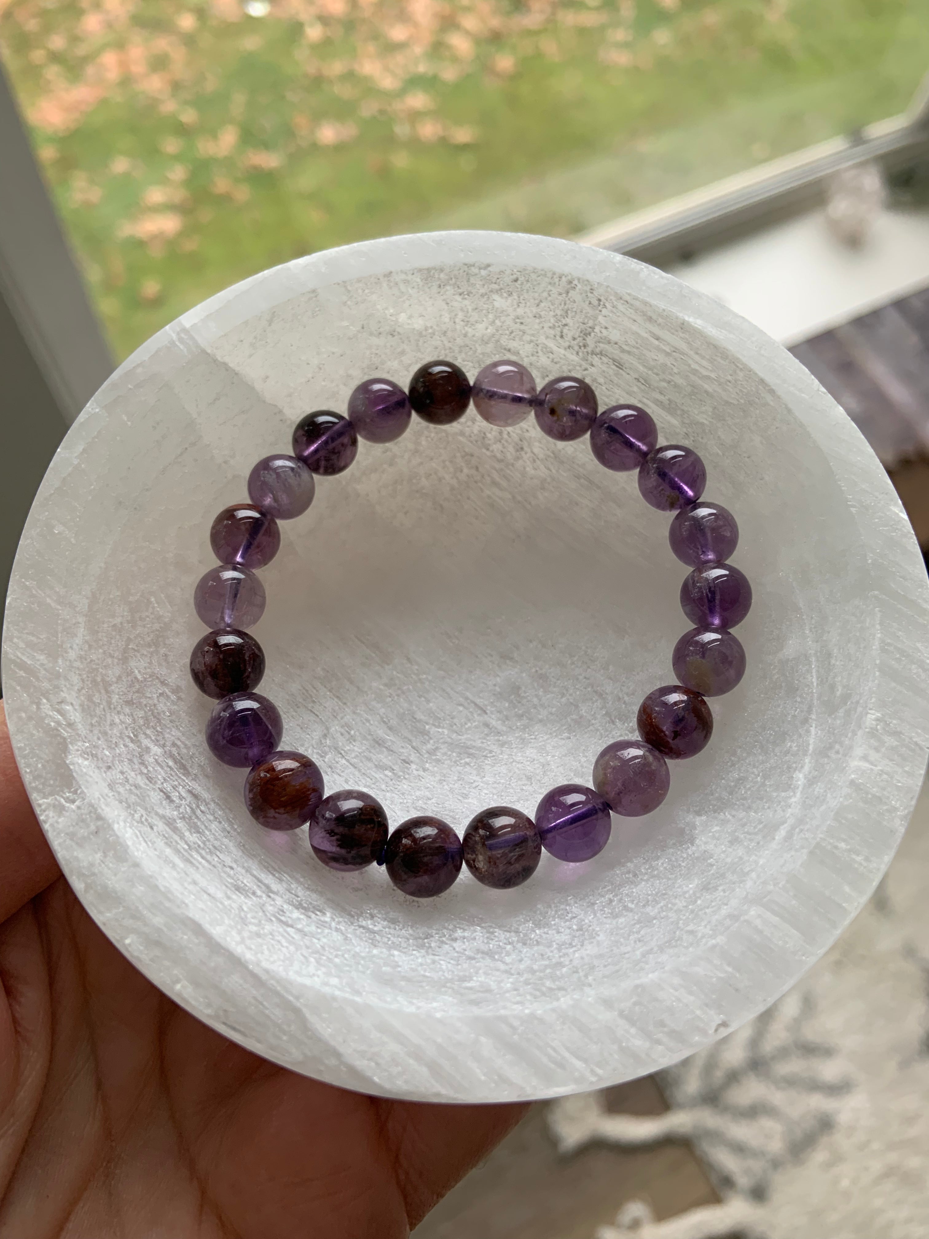 White Selenite crystal bowl holding gemstone beaded bracelet — charging jewelry with cleansing lunar energy