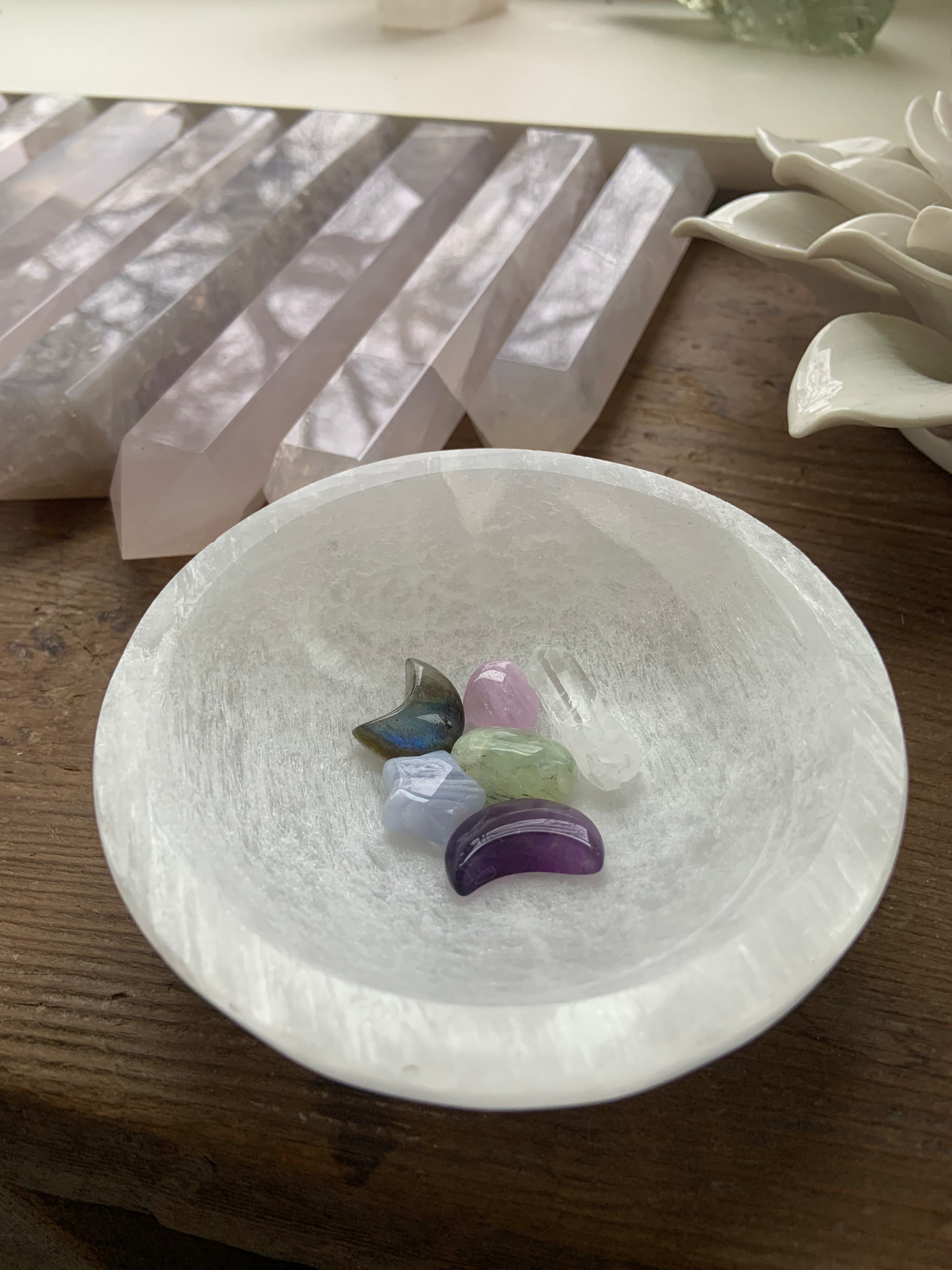 Wide lifestyle view of Selenite bowl with celestial carvings inside — altar crystal bowl for cleansing and recharging stones