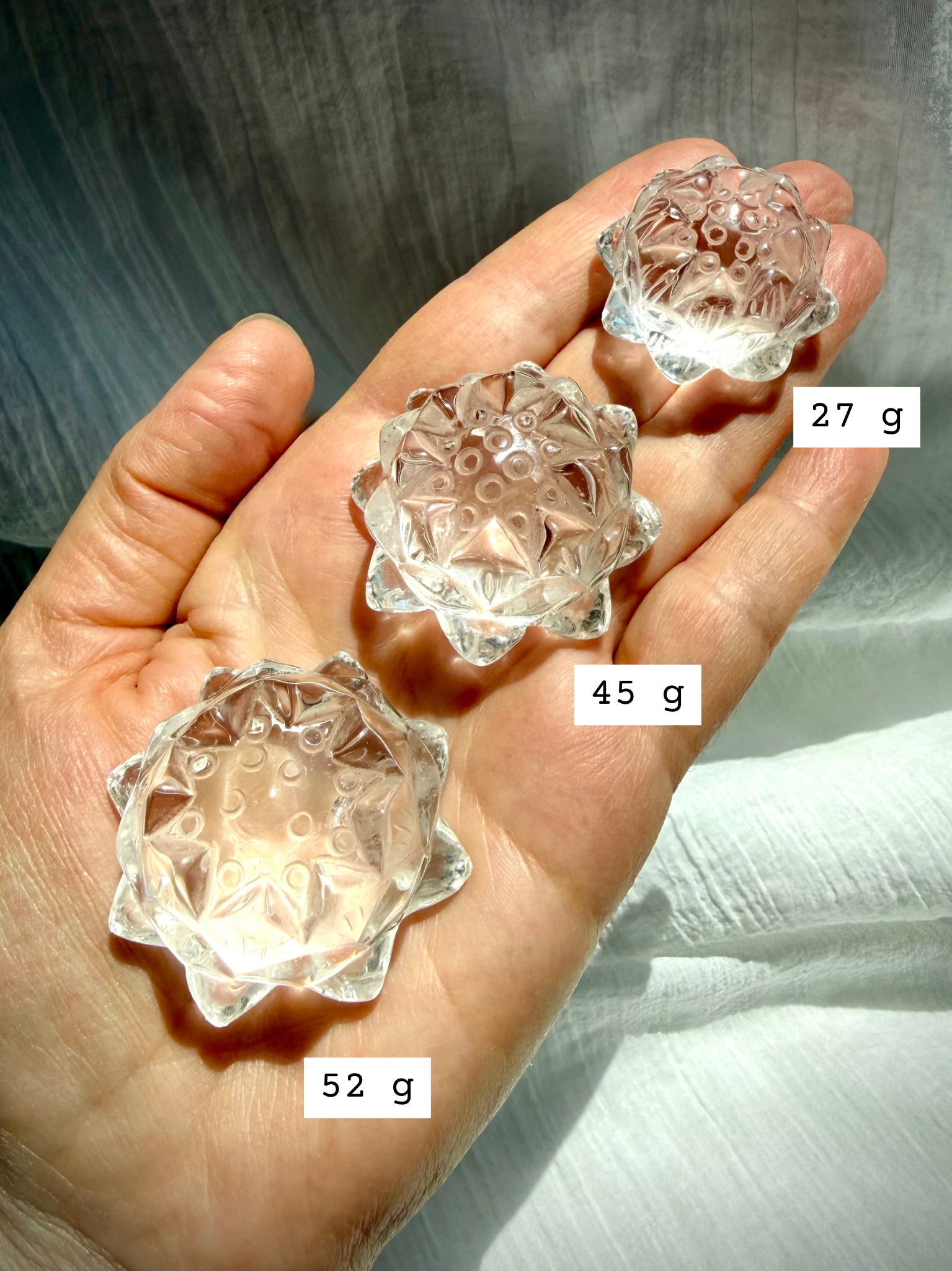 Small Clear Quartz crystal lotus flower carving held in hand marked with size, showing clarity and detailed petals
