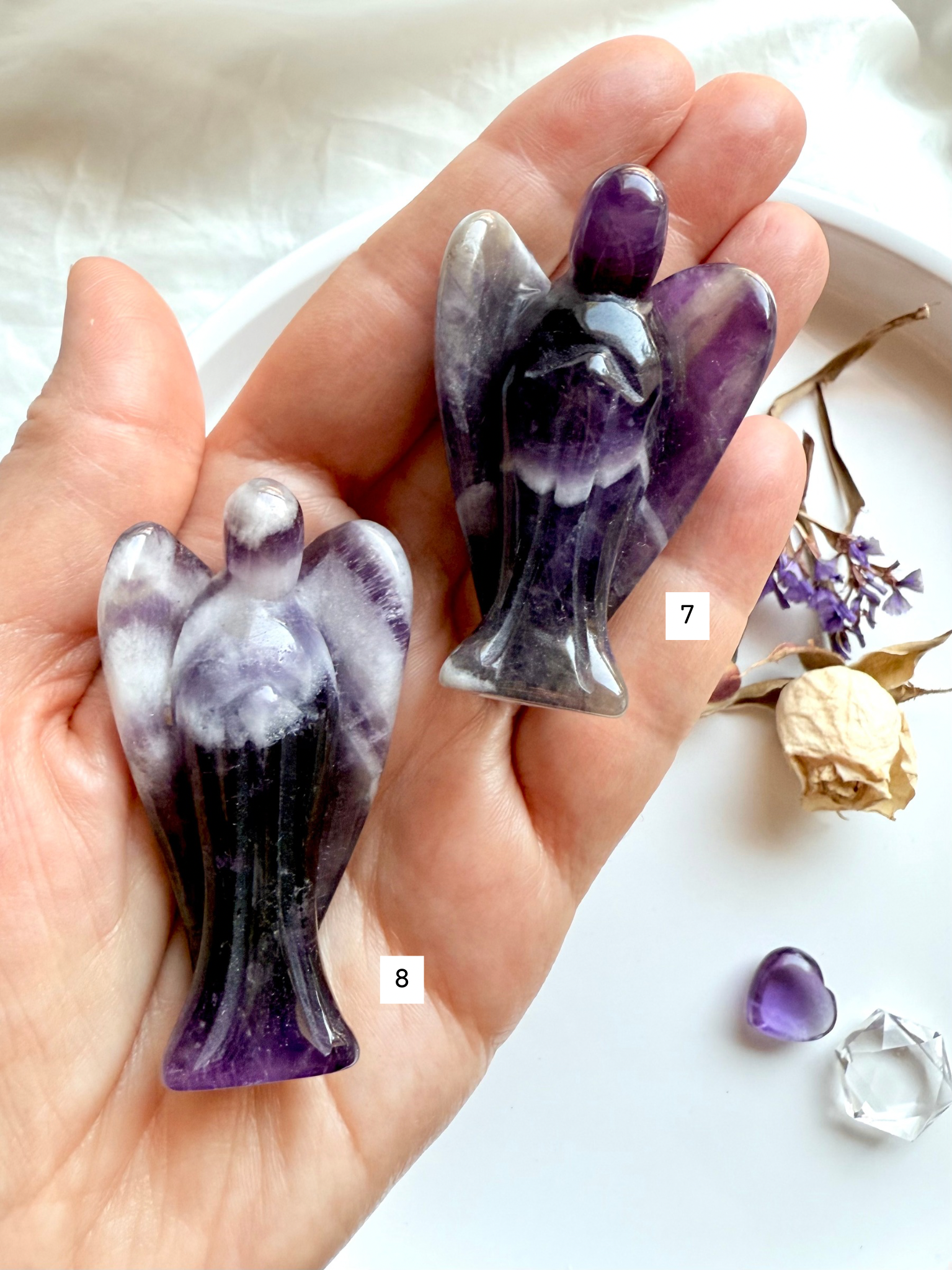 Dream Amethyst angels #7 and #8 held in hand, showing distinct chevron banding and deep purple hues – choose your own ethically sourced angel carving for healing, meditation, and spiritual gifting