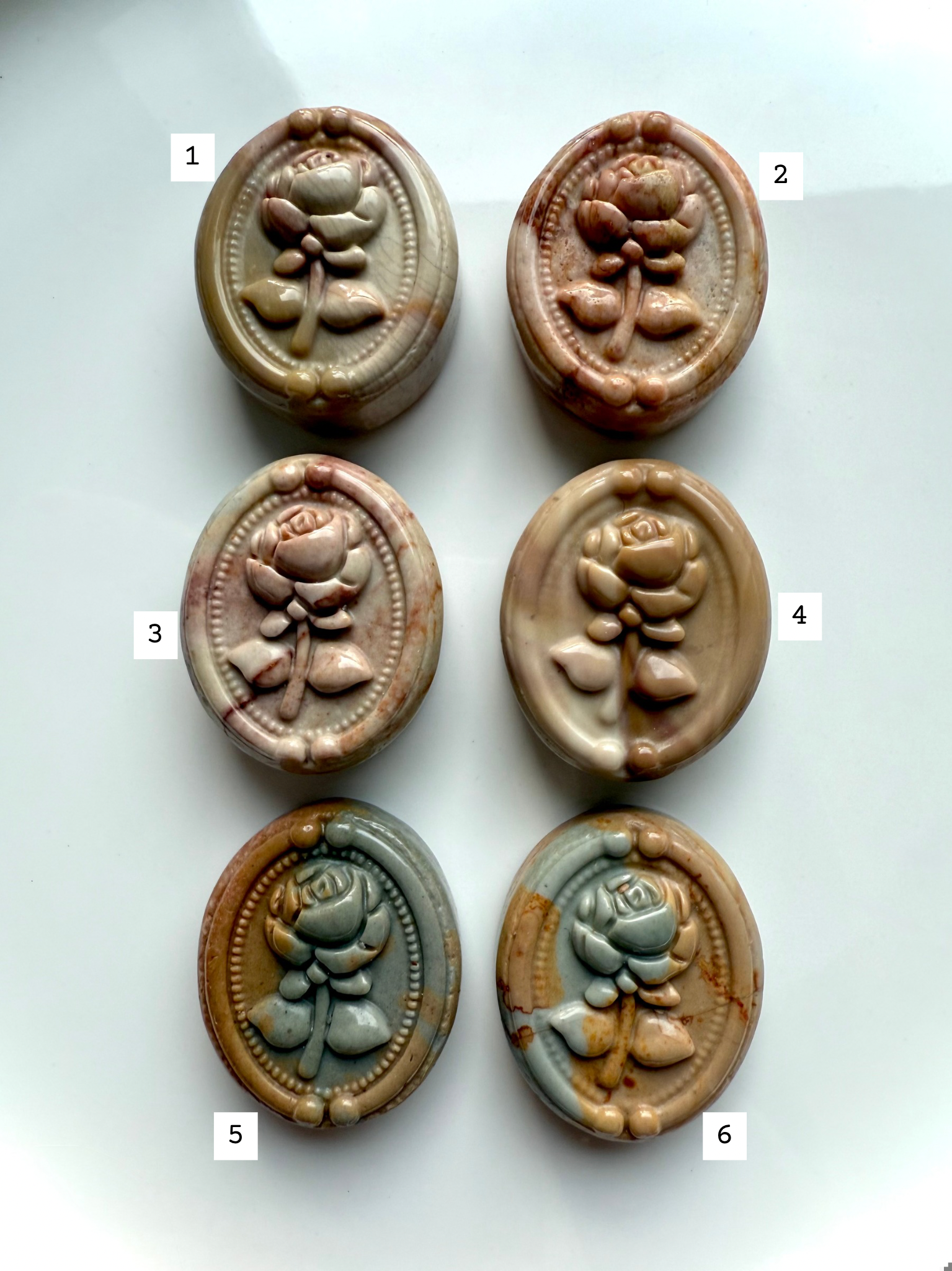Polychrome Jasper rose cabochons in assorted natural colors arranged in two rows — carved crystal ovals for grounding, balance, and earth element healing.