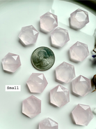 Small rose quartz hexagon crystals with a quarter for scale on a light background