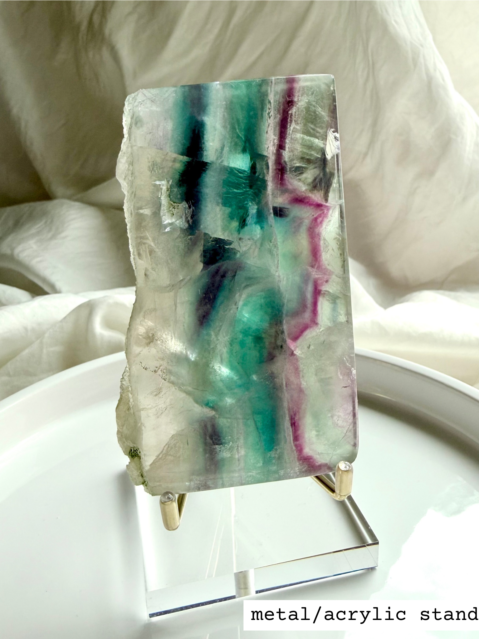 Statement fluorite slab crystal with luminous rainbow banding shown on elegant display stand