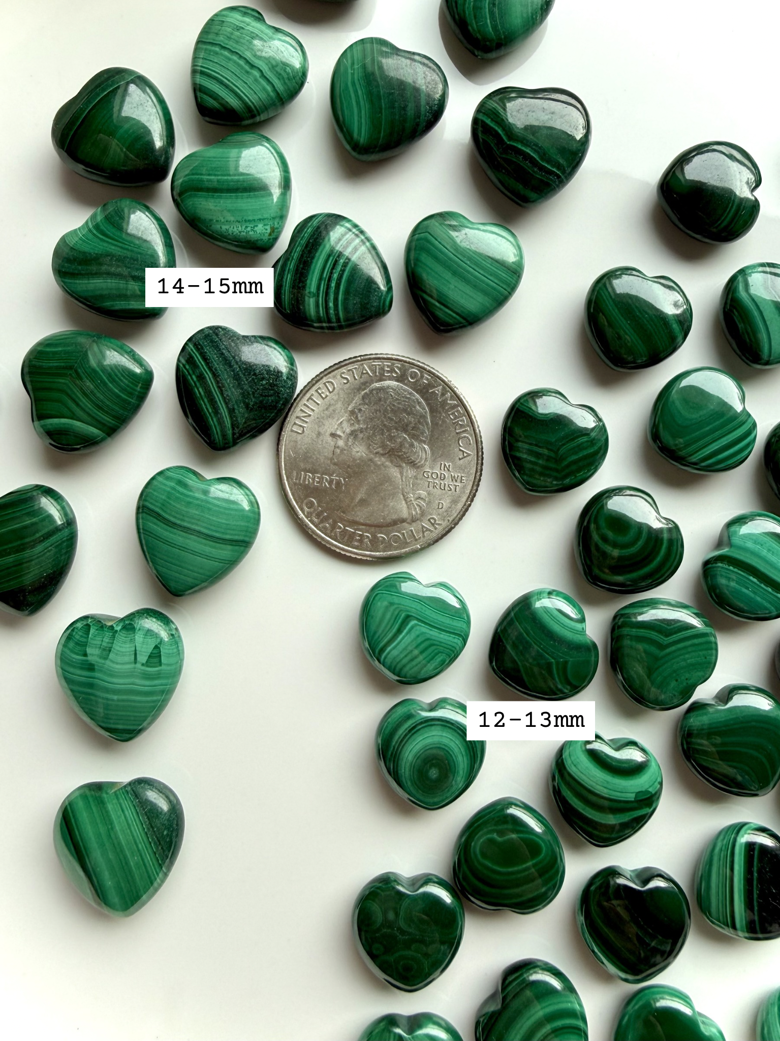 Two sizes of mini malachite hearts arranged with a US quarter for size reference