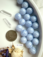 High quality 13-14 mm Blue Lace Agate Spheres shown with a US quarter for scale and quartz points