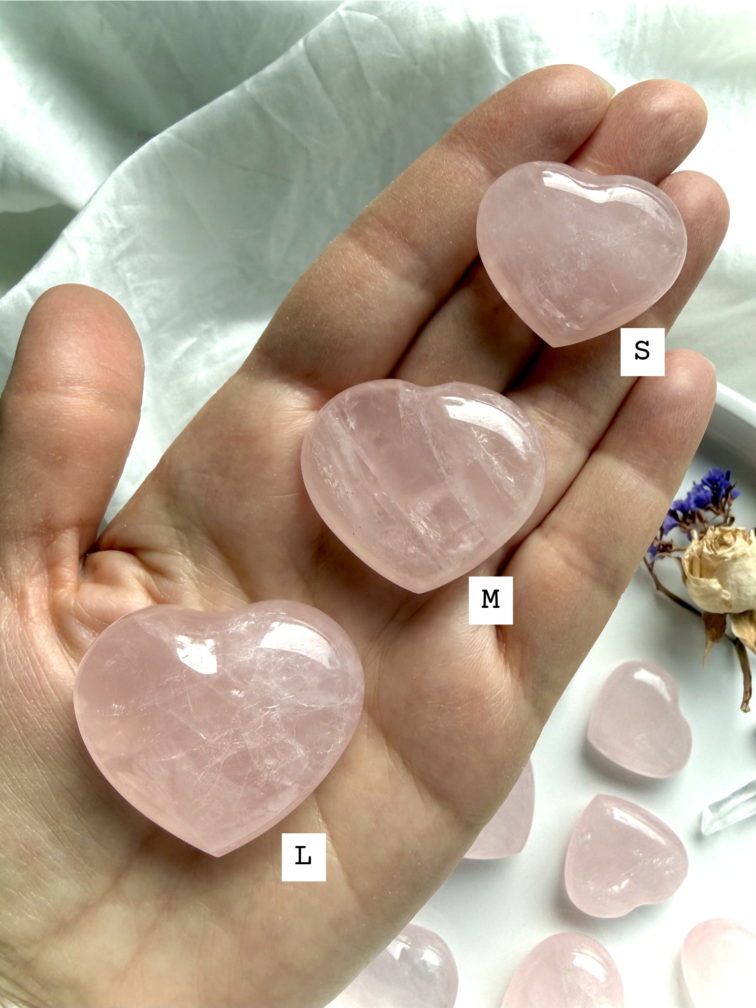 Rose quartz hearts held in hand showing size and soft pink translucency, polished crystal hearts for love and comfort