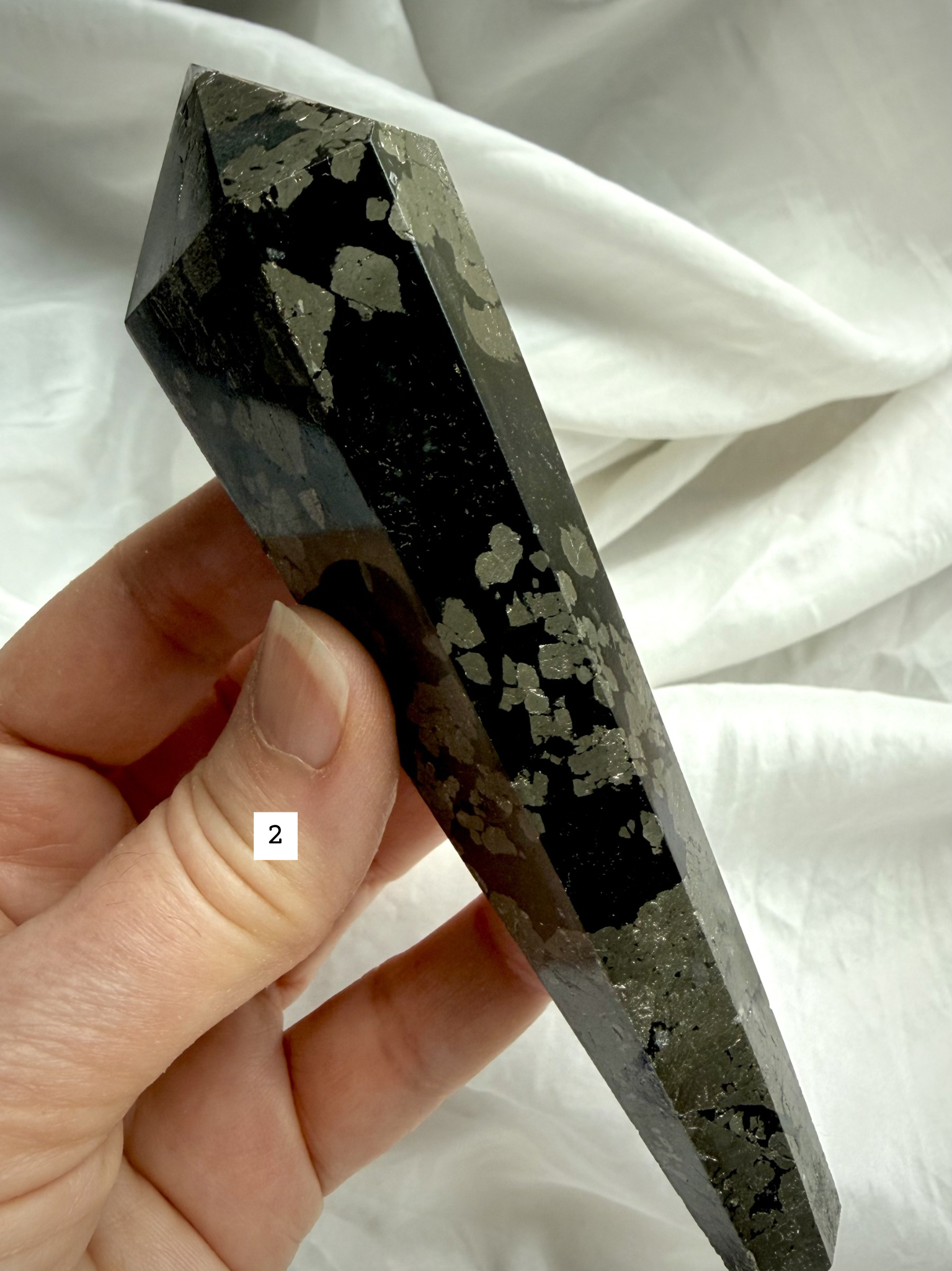 pyrite wand in black matrix held in hand polished crystal point option 2