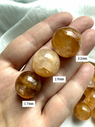 golden healer quartz mini spheres in hand showing size scale and natural variation between pieces
