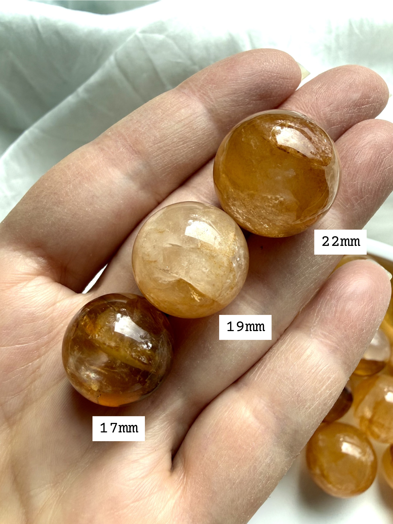 golden healer quartz mini spheres in hand showing size scale and natural variation between pieces
