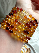 Close-up of polished Baltic amber bead bracelets in warm golden, honey, and cognac tones – Solar Plexus crystal jewelry for energy, confidence + vitality