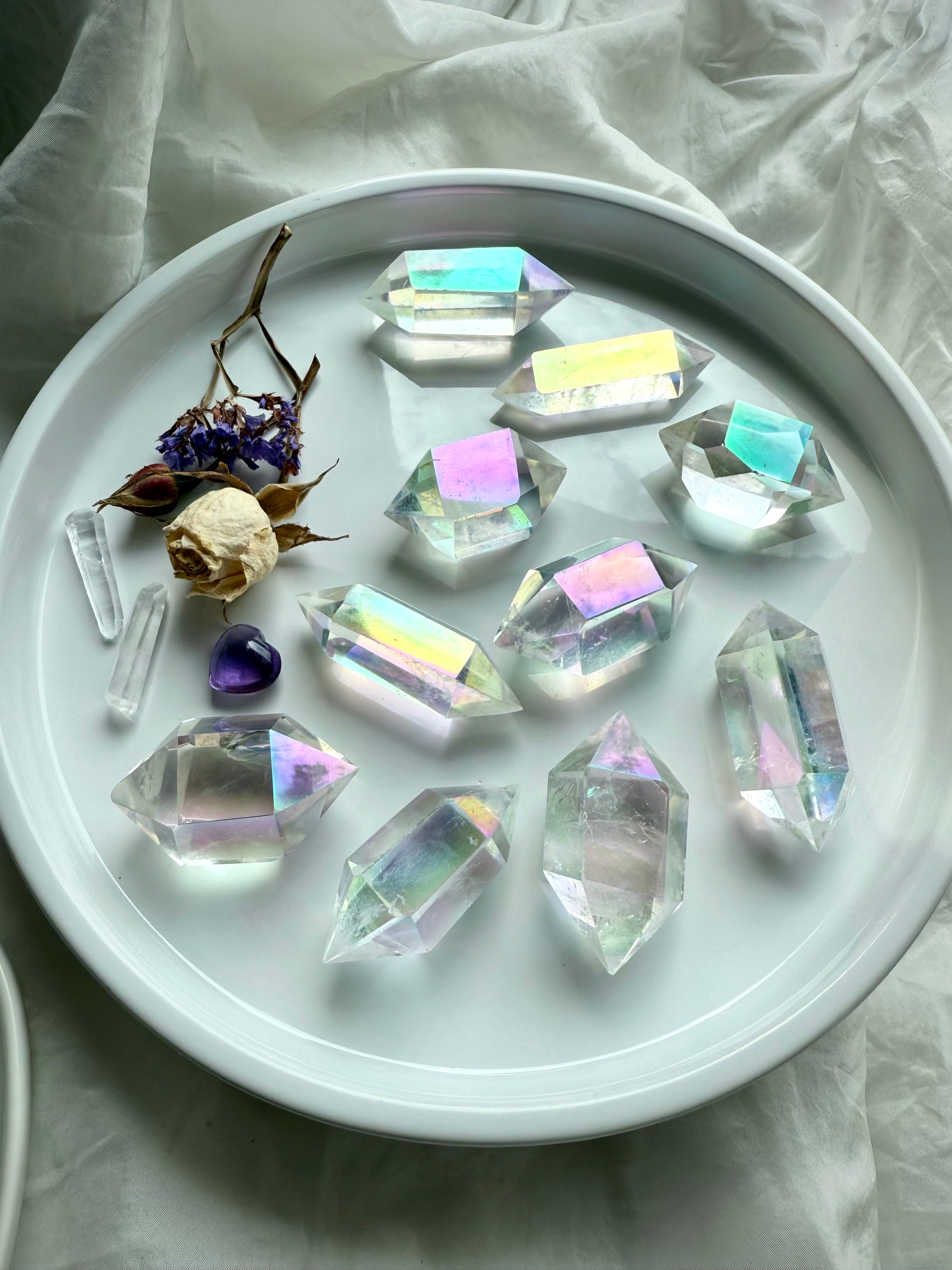 Angel Aura Quartz double terminated points with pastel rainbow glow displayed in a white dish for meditation and chakra healing