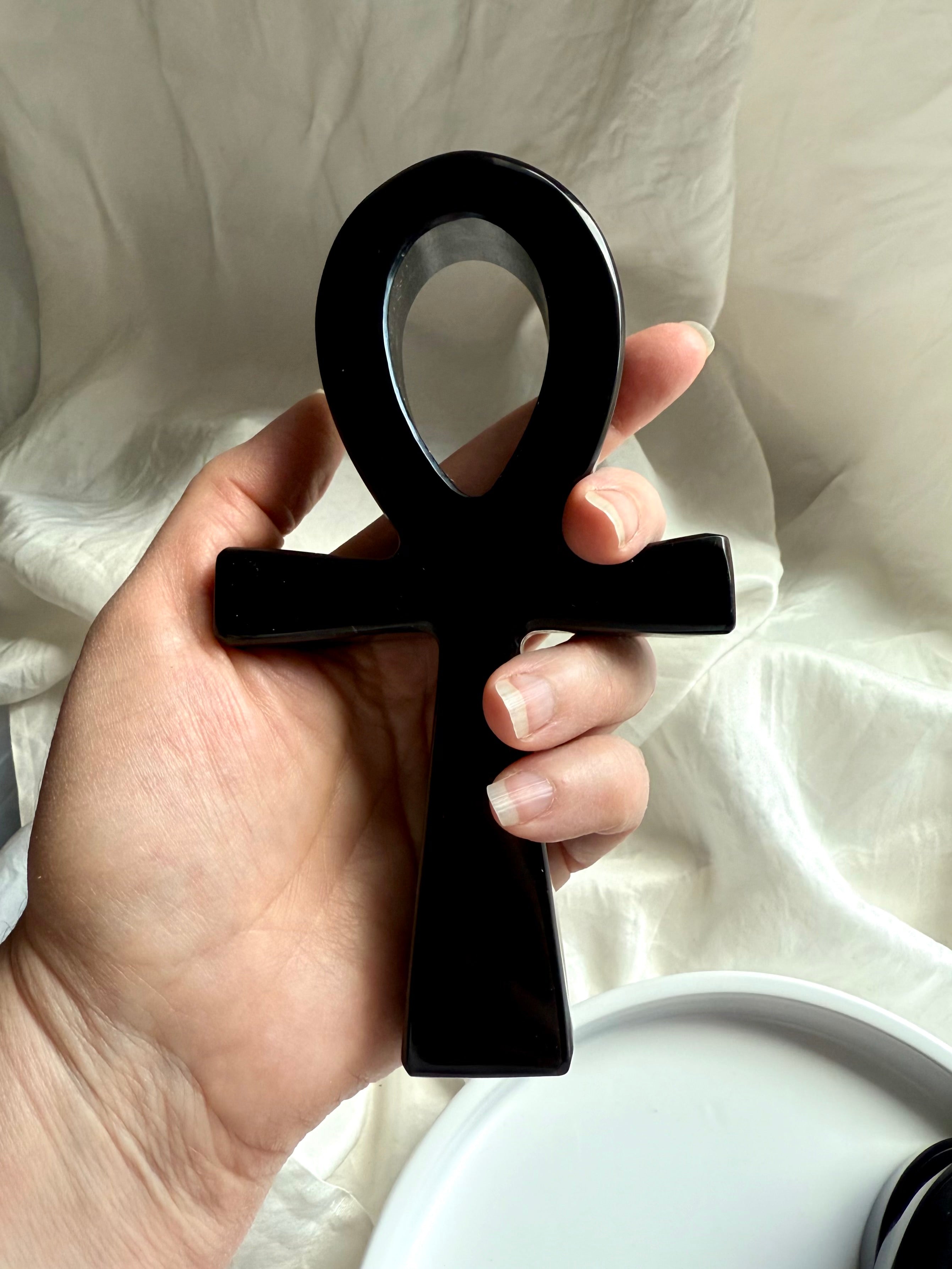 Hand-carved black obsidian ankh carving held in hand — sacred Egyptian crystal symbol of eternal life and protection.