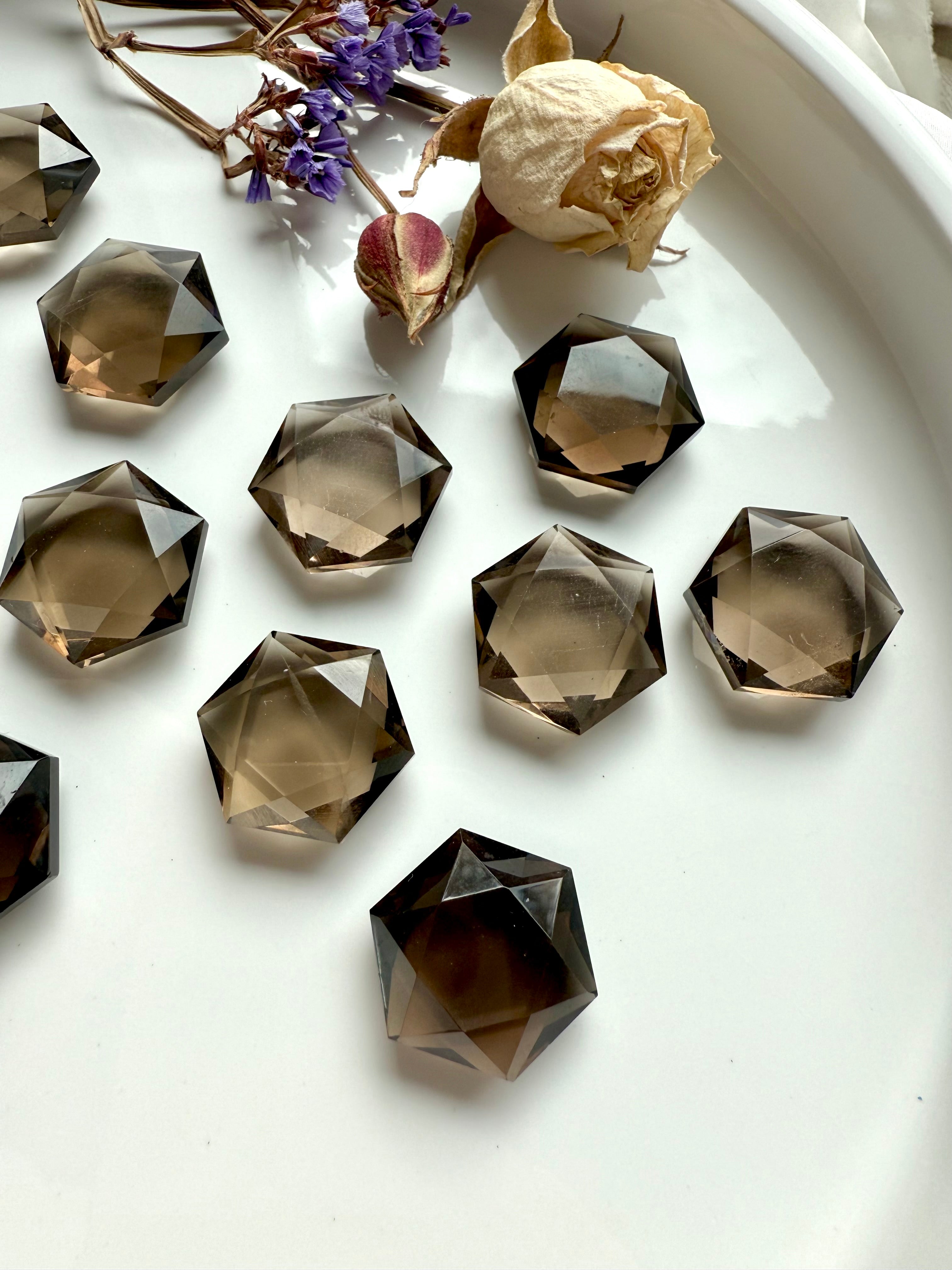 Smoky quartz hexagon crystals with dried rose and purple statice flowers – faceted healing stones for spiritual grounding and chakra alignment.