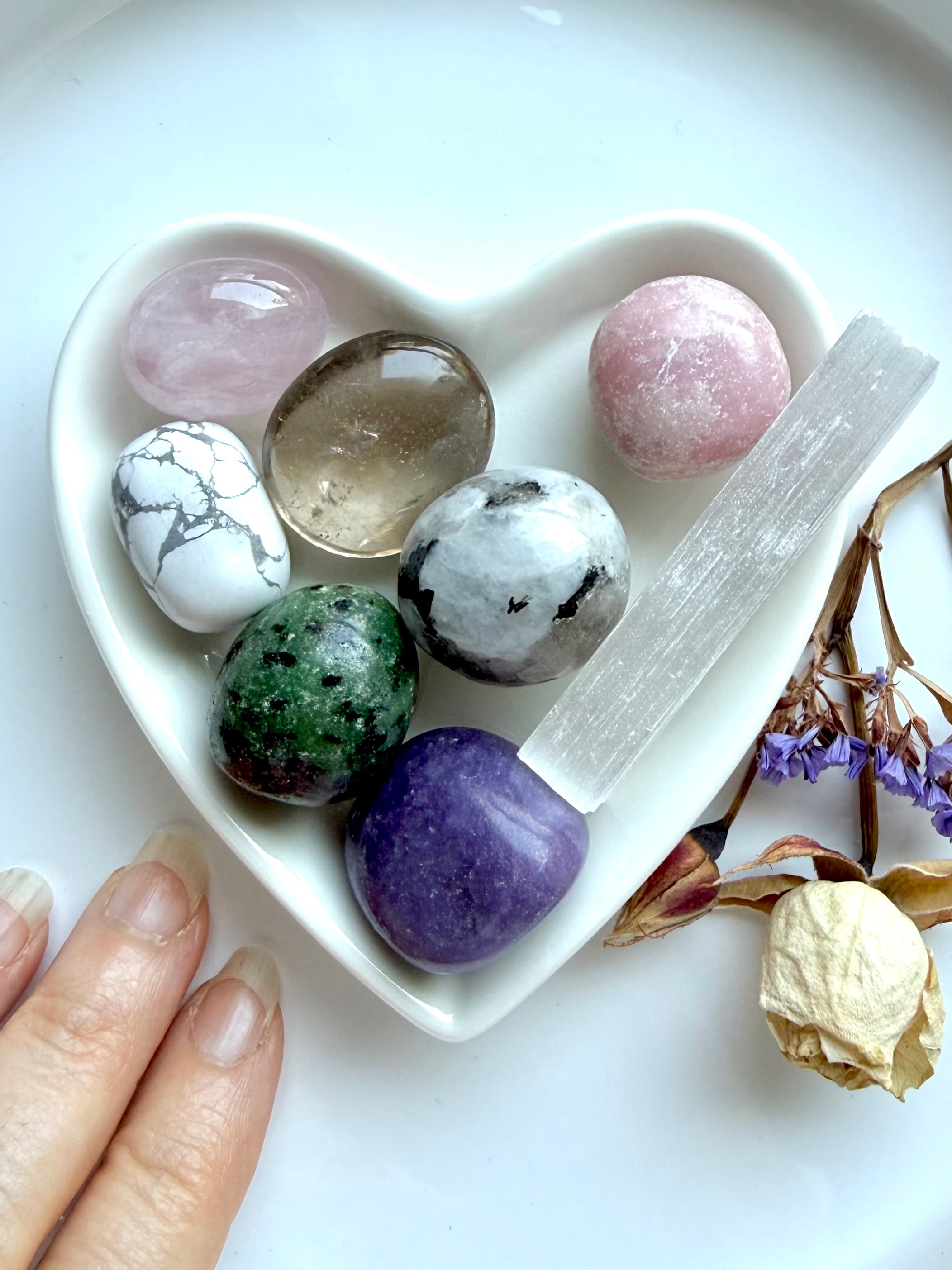 crystals for grief and loss healing set in white ceramic heart bowl with rose quartz, lepidolite, rainbow moonstone, ruby zoisite, howlite, smoky quartz, and selenite for comfort and emotional healing