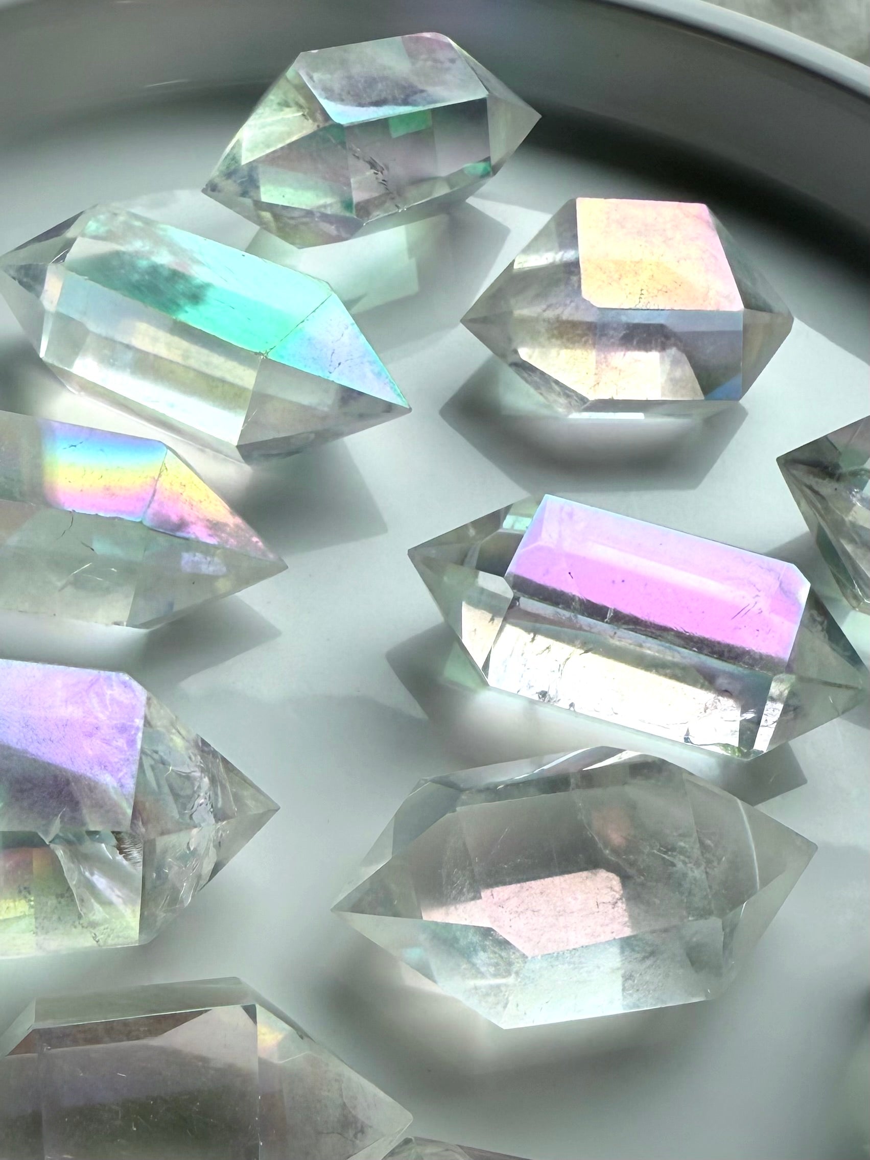 Shimmering Angel Aura Quartz double terminated points with pastel rainbow hues displayed in natural light