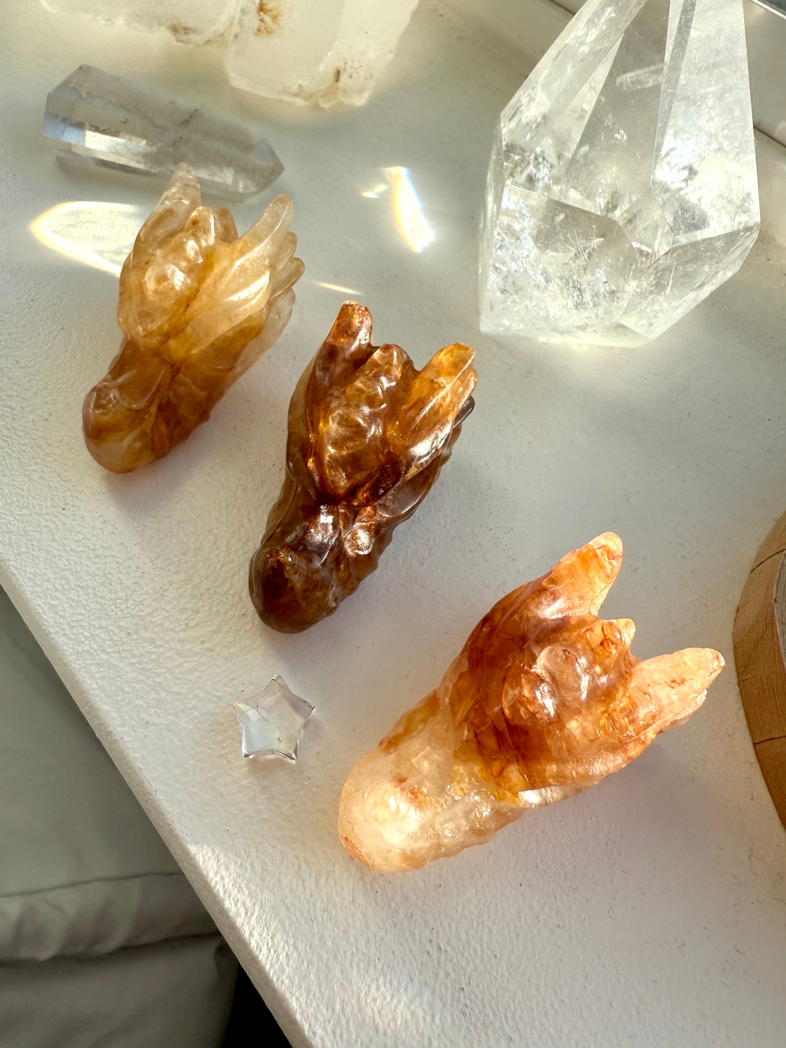 Overhead view of three small Golden Healer Quartz dragon head carvings on windowsill — crystal figurines for Solar Plexus healing, energy work, and spiritual décor.