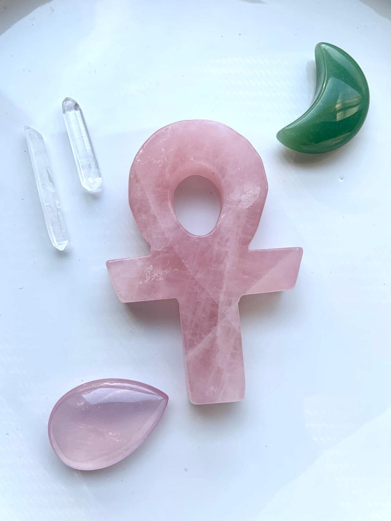 Hand Carved Rose Quartz Crystal Ankh, shown on a white plate with some other crystals