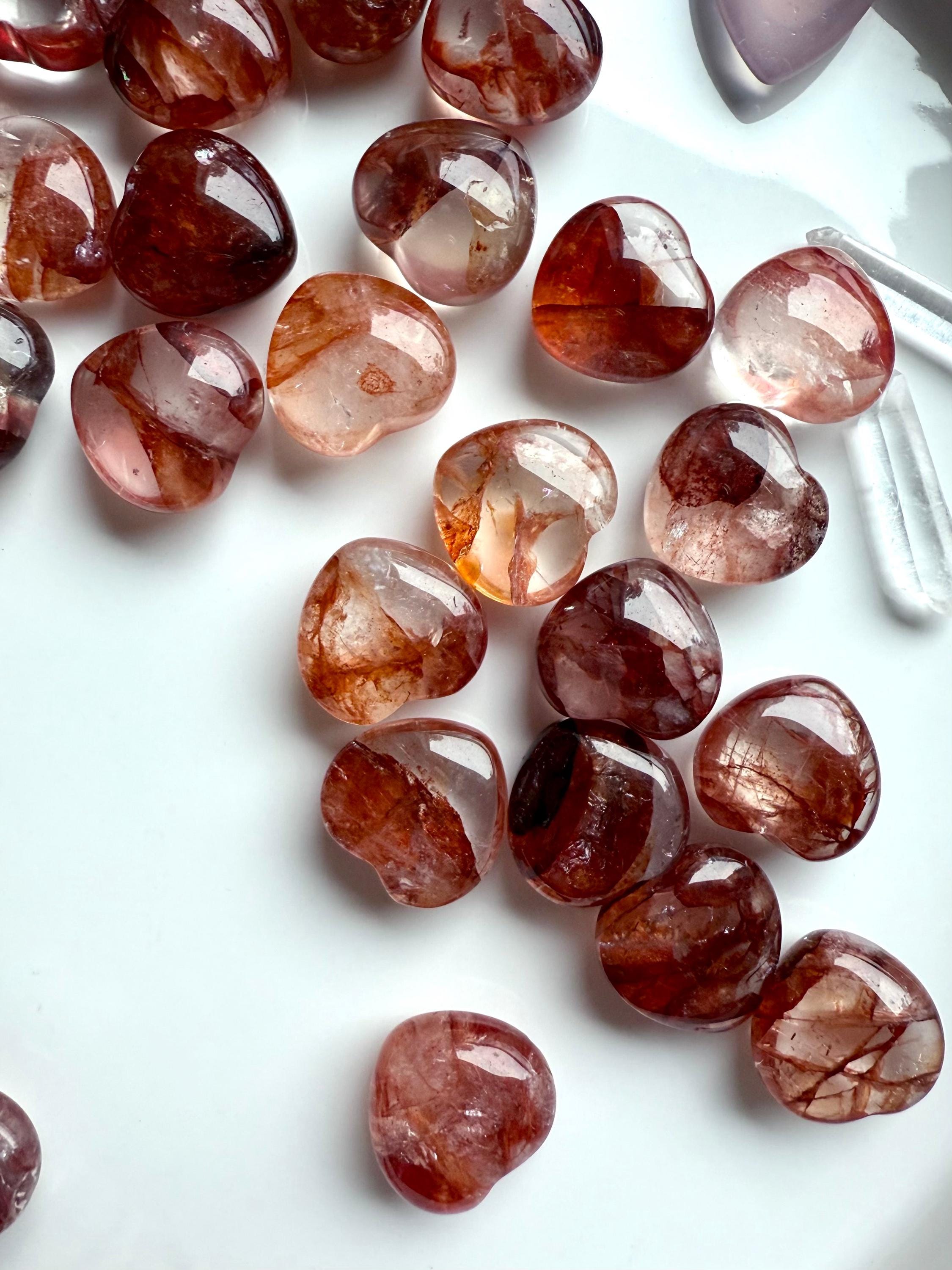 Collection of red Hematoid Quartz hearts in natural light, shown on a white plate