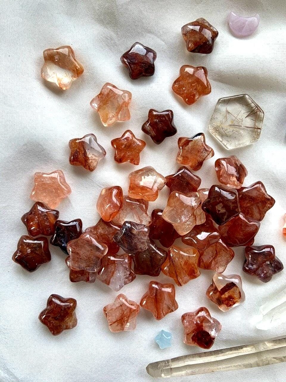 An array of Mini Fire Quartz Crystal Stars shown on a white background with some other crystals