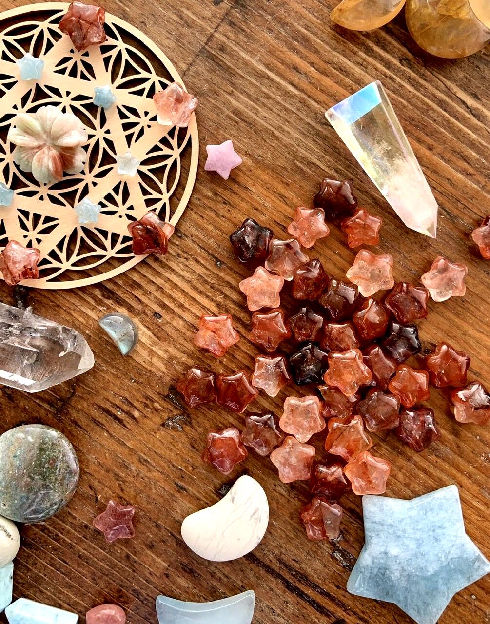 Mini Fire Quartz Crystal Stars shown on a wood table with a crystal grid + crystal collection