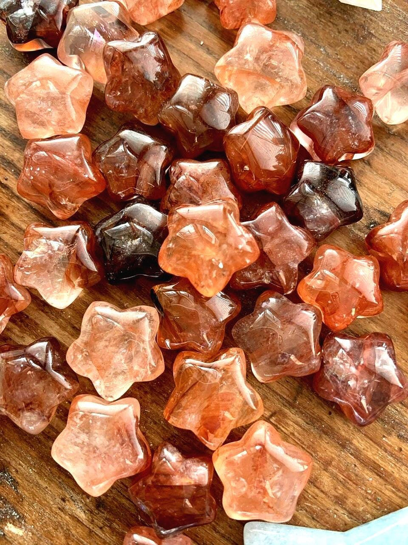 A close up of our vibrant red fire quartz mini crystal star shapes shown on a wood table 