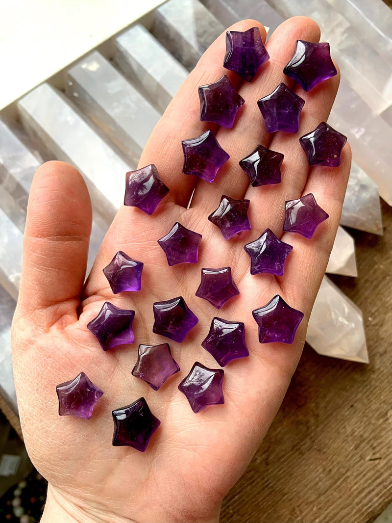Mini sized purple amethyst stars shown on my hand with pretty crystals in the background