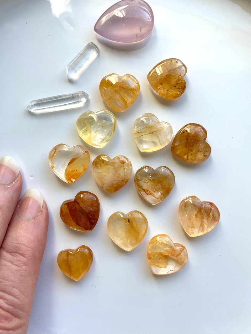 Golden Healer Heart Shaped Mini Crystal Carvings shown on a white plate with a few other crystals