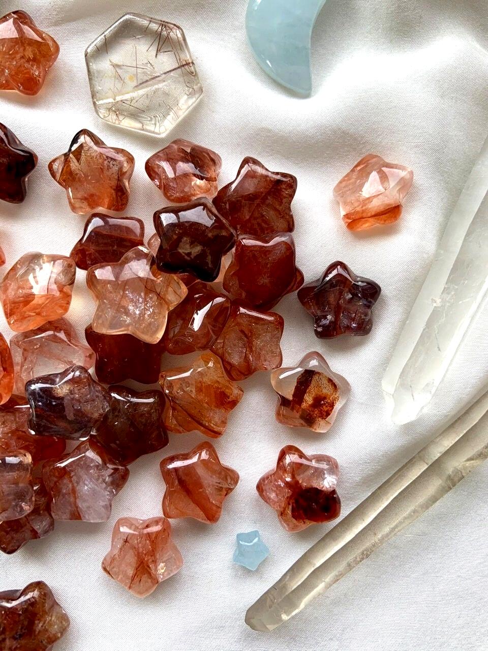 An array of vibrant red Mini Fire Quartz Crystal Star carvings shown on a white background