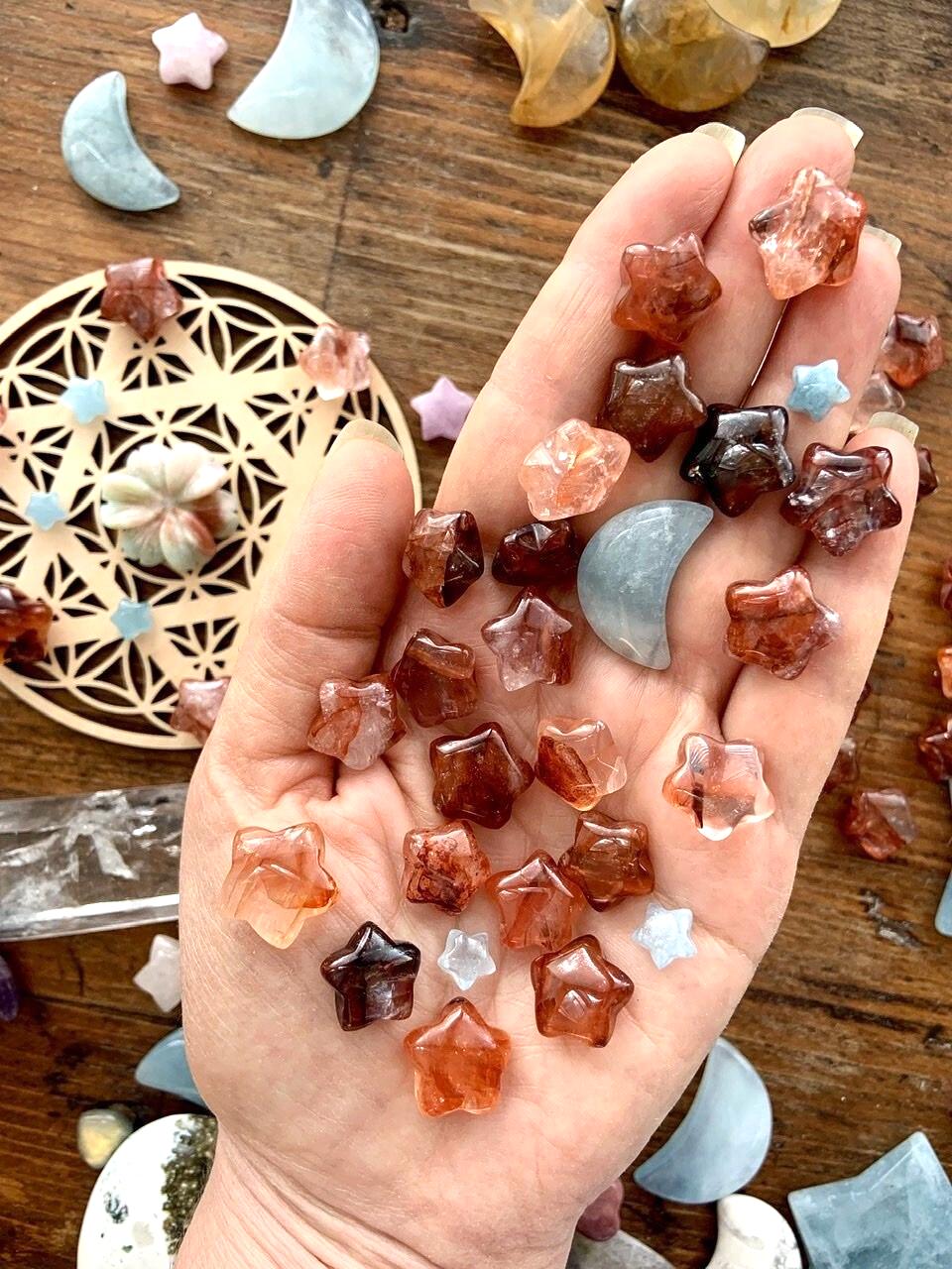 Mini Fire Quartz Crystal Stars shown on a my hand for scale with a crystal grid + crystal collection