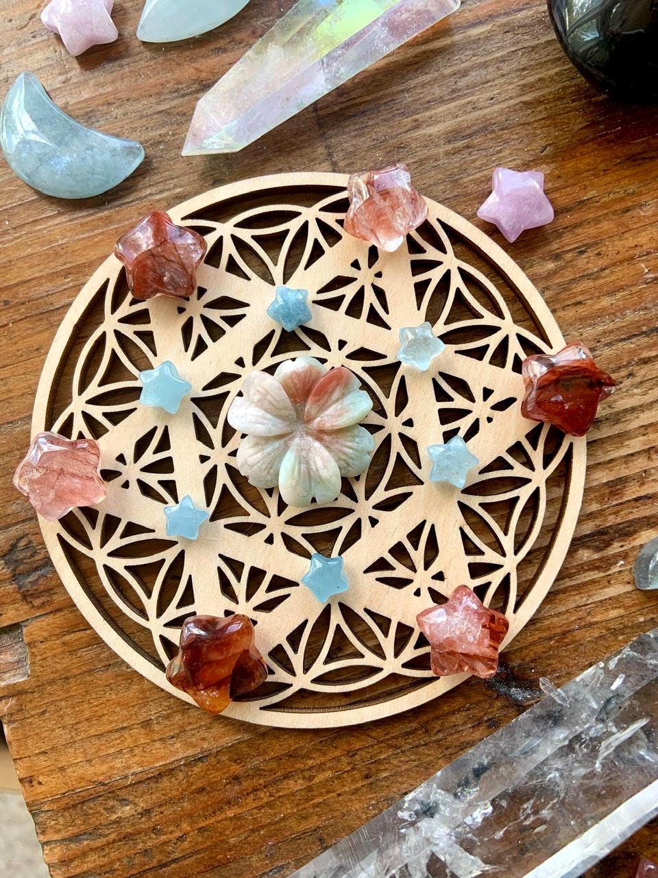 A crystal grid with Mini Fire Quartz Crystal Stars shown on a wood table with a crystal collection