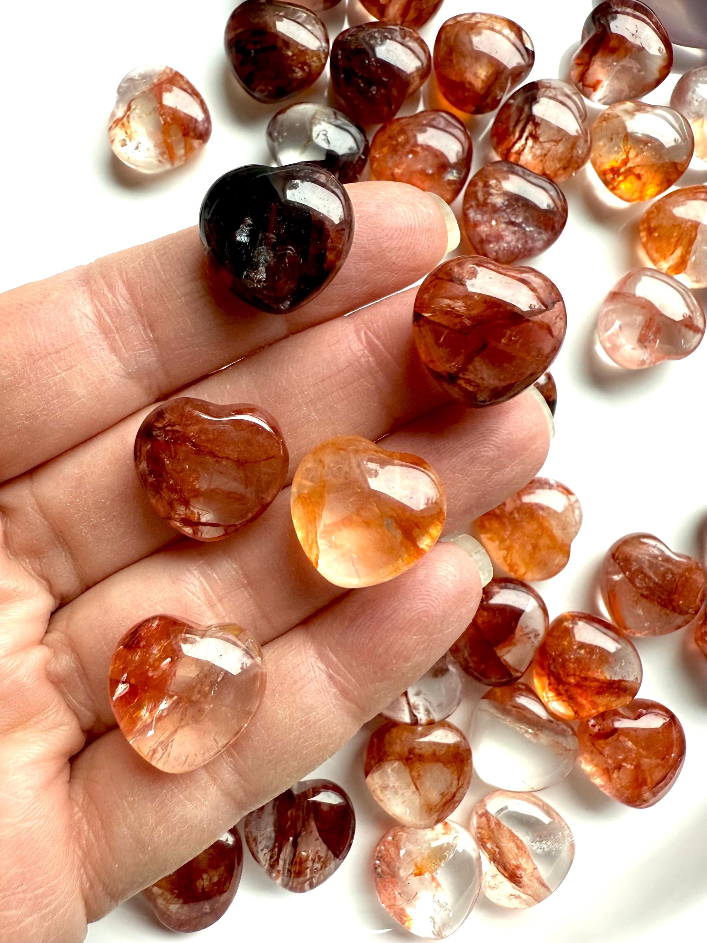 Close up of high quality Mini Fire Quartz Crystal Hearts shown on my fingertips for scale