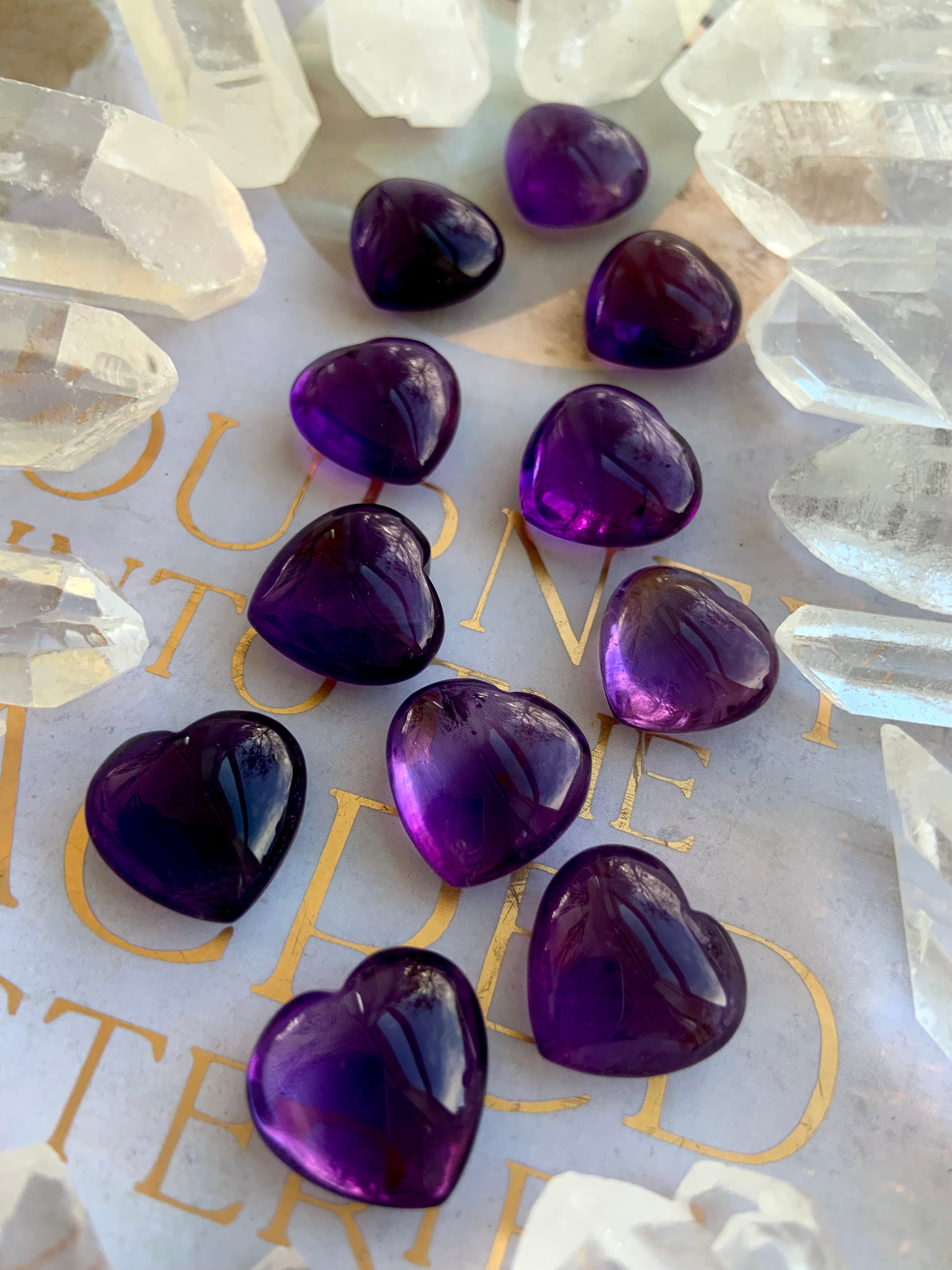 Angled shot of Mini Amethyst hearts surrounded by clear quartz points — purple crystal hearts for intuition and balance