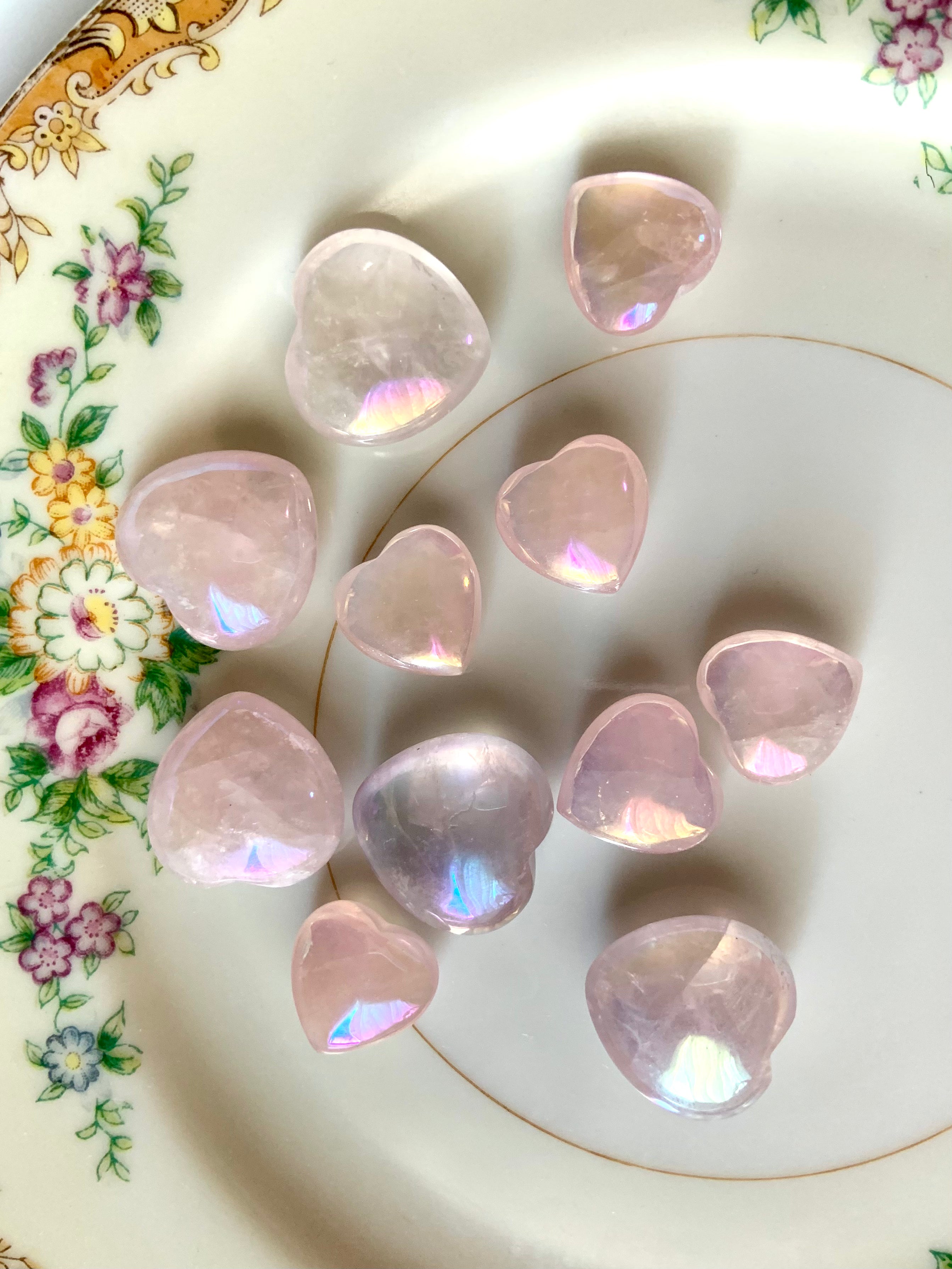 Close-up of translucent pink aura rose quartz hearts on a plate with floral cottagecore details — dreamy angel aura crystals for love & heart healing
