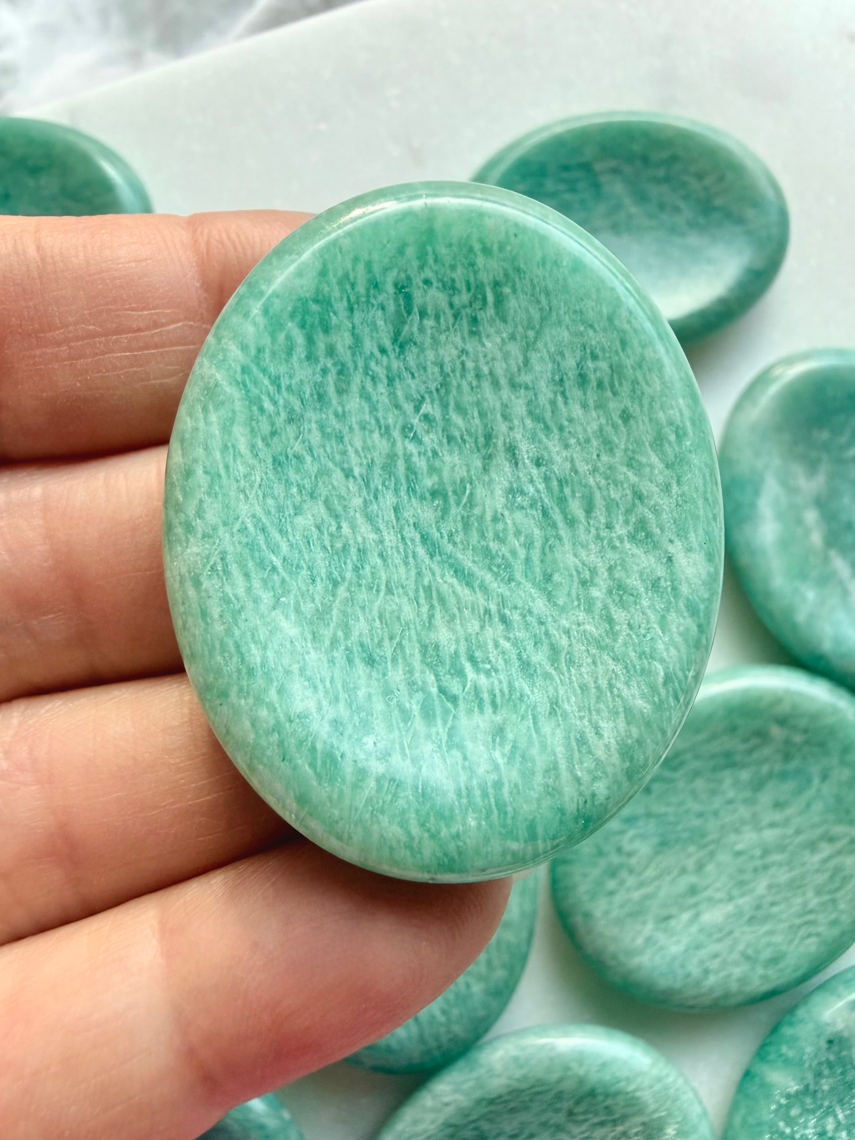Close-up of polished Amazonite worry stone showing delicate mineral patterns, soft green coloring and a comfortable oval shape