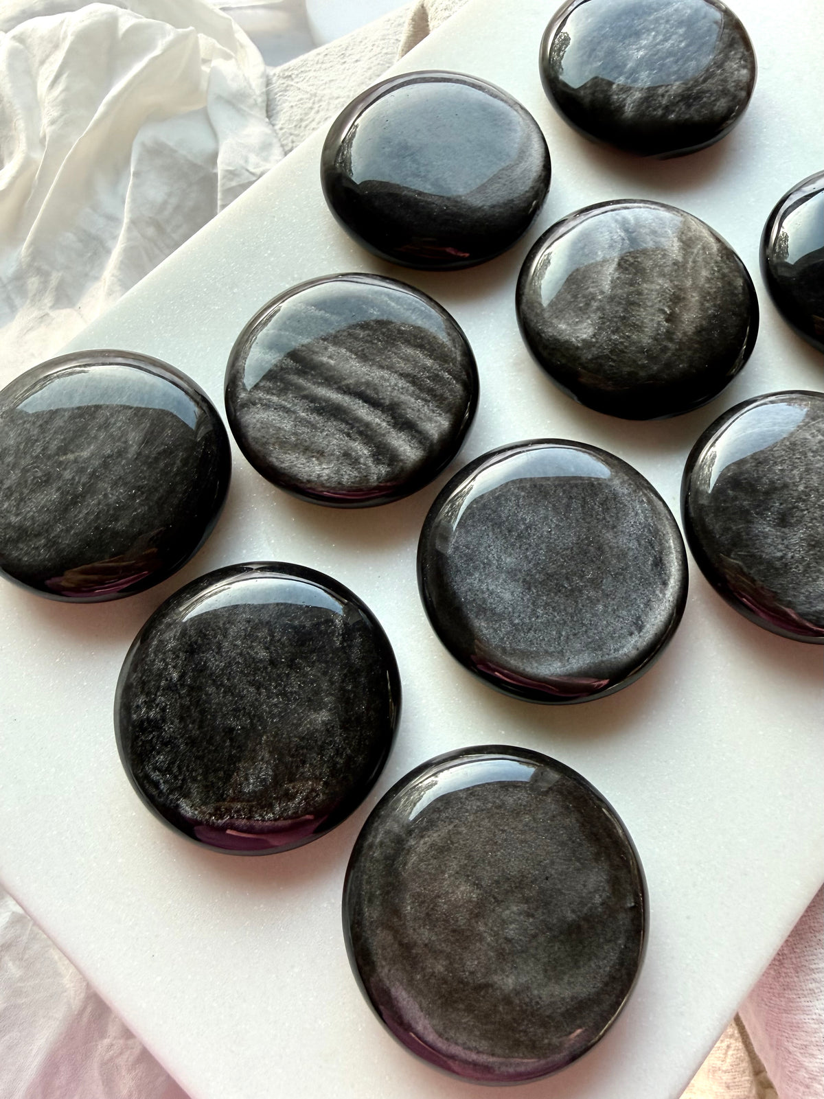 Silver Sheen Obsidian palm stones with shimmering silver and graphite patterns on polished black round crystals