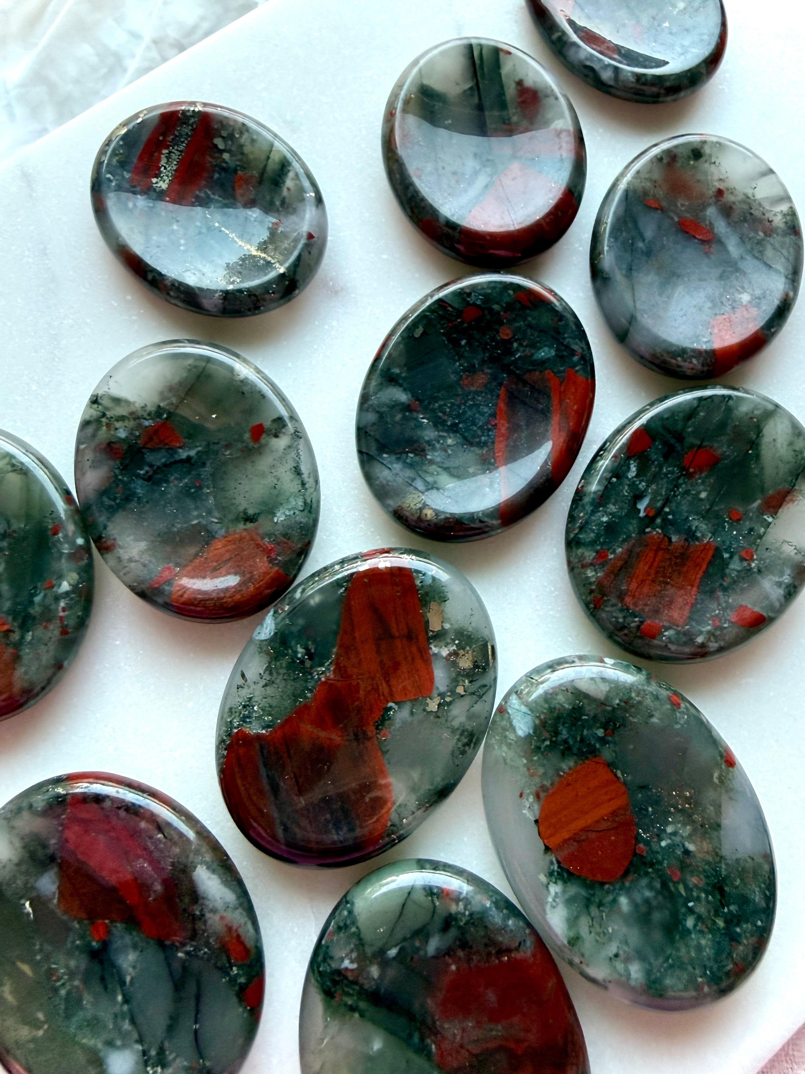 Assortment of Bloodstone worry stones displaying unique green and red mineral patterns, healing crystals for vitality and resilience