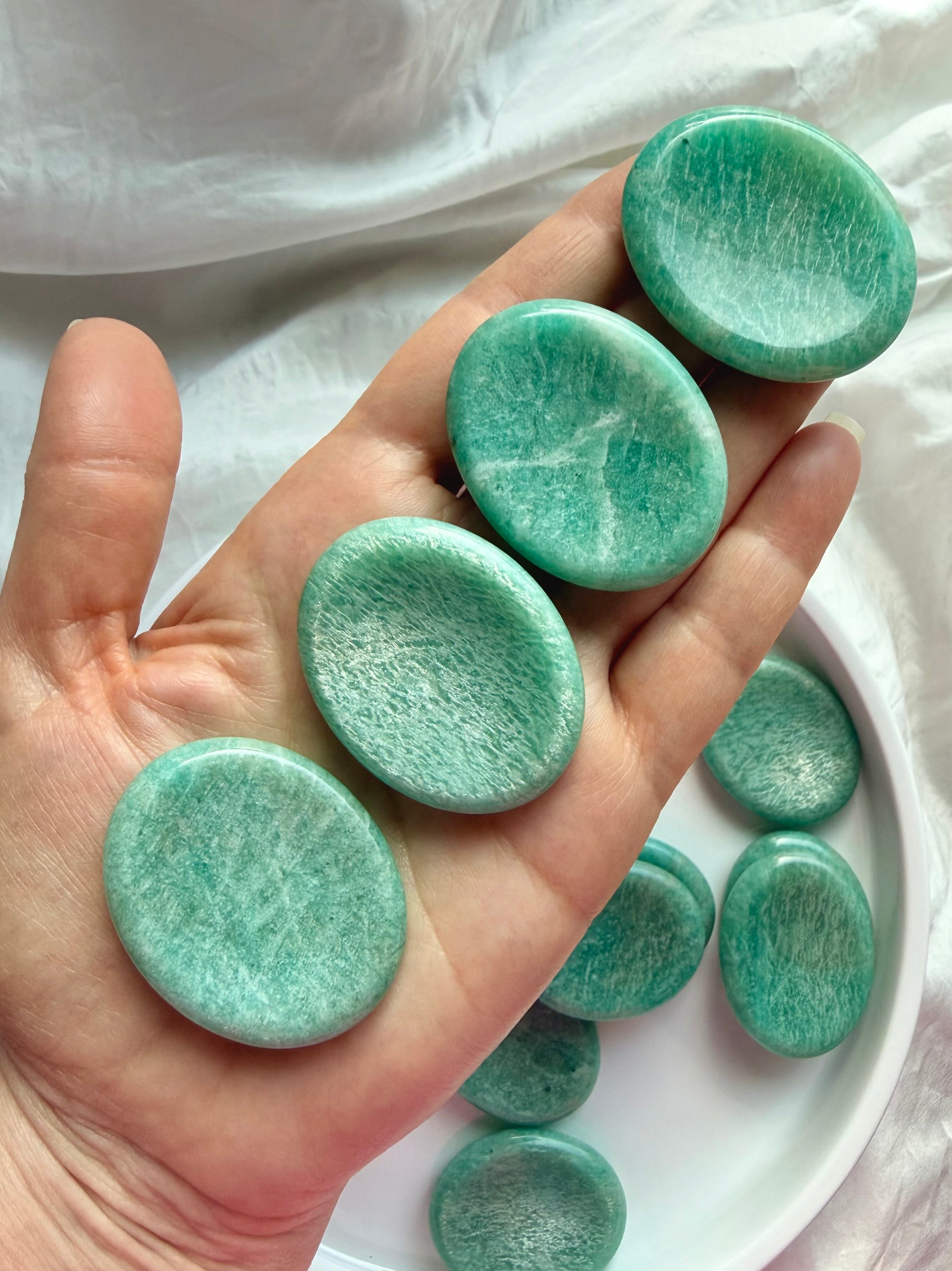 Amazonite worry stones displayed in hand, smooth oval pocket crystals for Throat Chakra healing, communication and self-expression