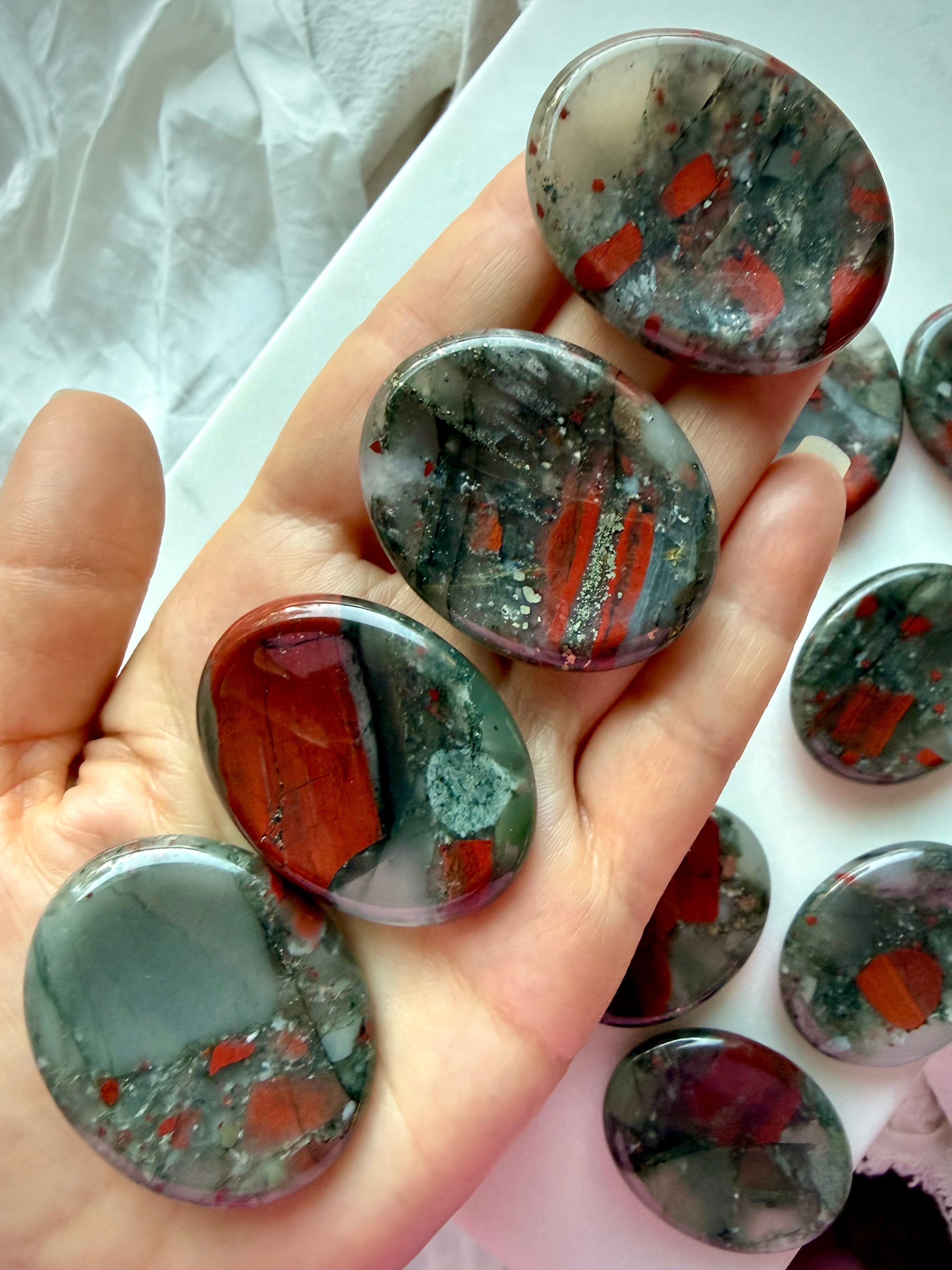 Bloodstone worry stones displayed in hand showing smooth polished oval shapes and natural red and green color variations