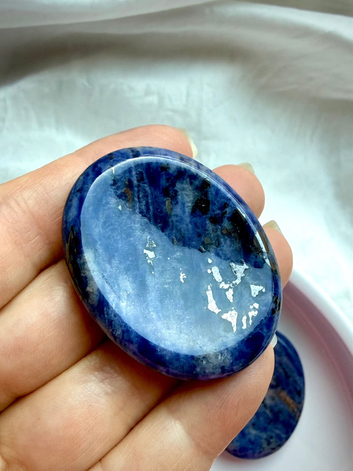 Sodalite worry stone held in hand showing smooth oval shape and thumb indentation for relaxation and mindful grounding
