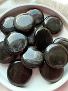 Silver Sheen Obsidian palm stones arranged in a bowl, shimmering black crystals for meditation and New Moon rituals