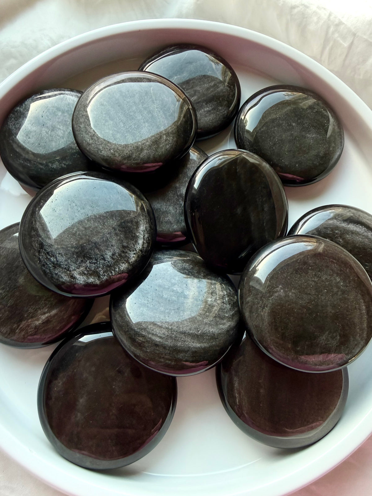 Silver Sheen Obsidian palm stones arranged in a bowl, shimmering black crystals for meditation and New Moon rituals