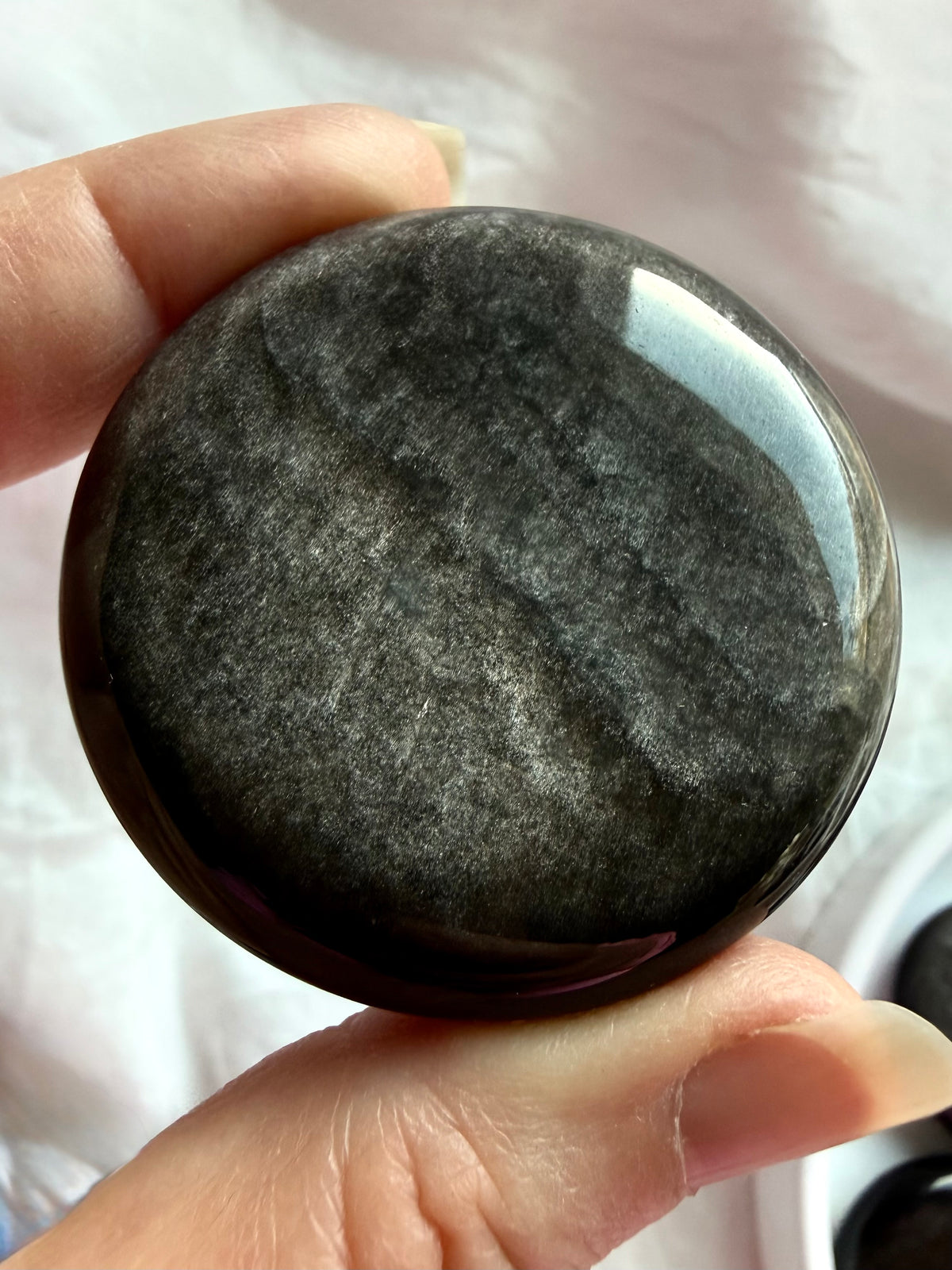 Round Silver Sheen Obsidian palm stone displaying soft metallic silver shimmer and natural cloud-like patterns