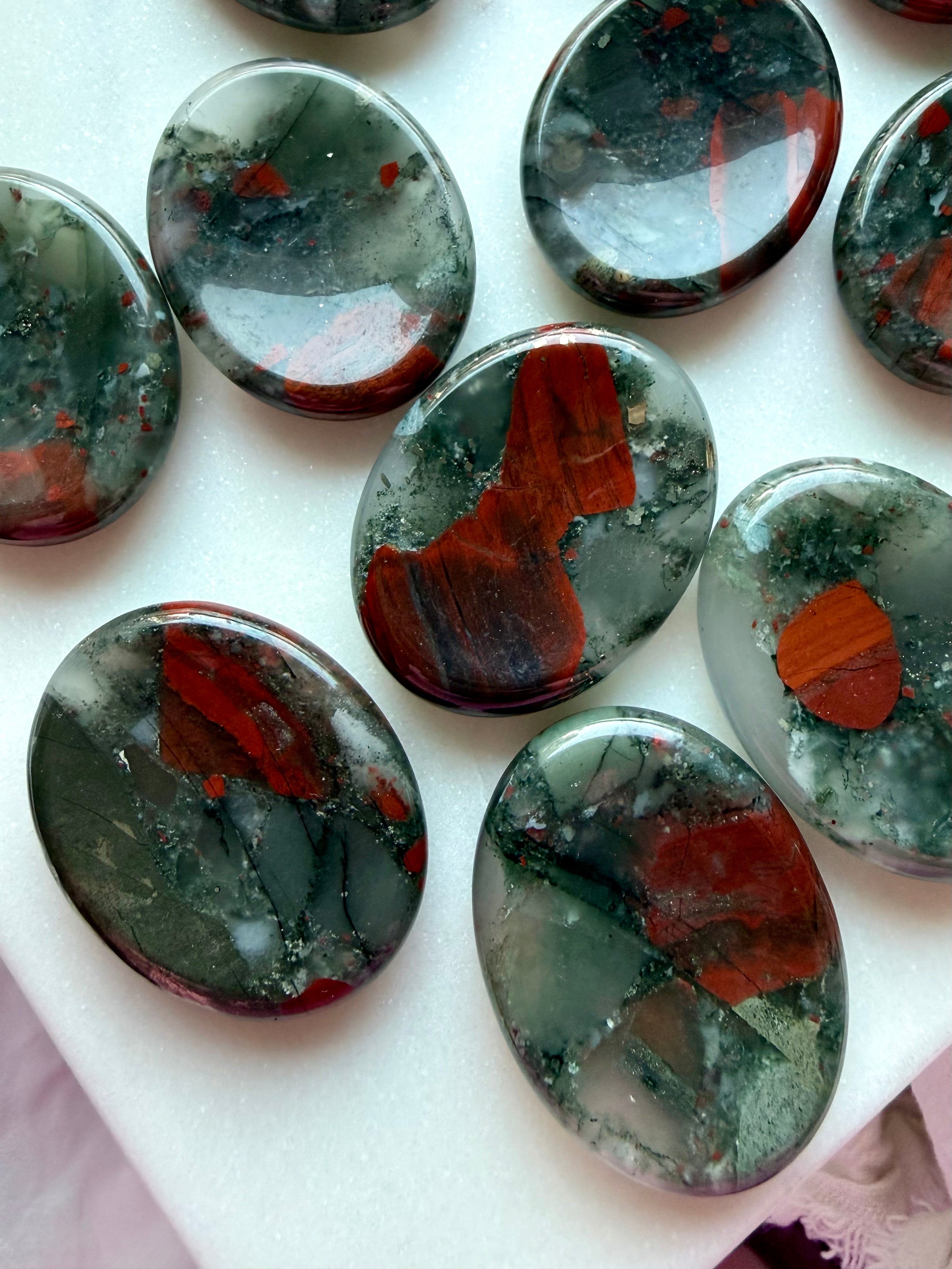 Bloodstone worry stones with deep forest green coloring and striking red mineral inclusions, polished grounding crystals for strength and courage