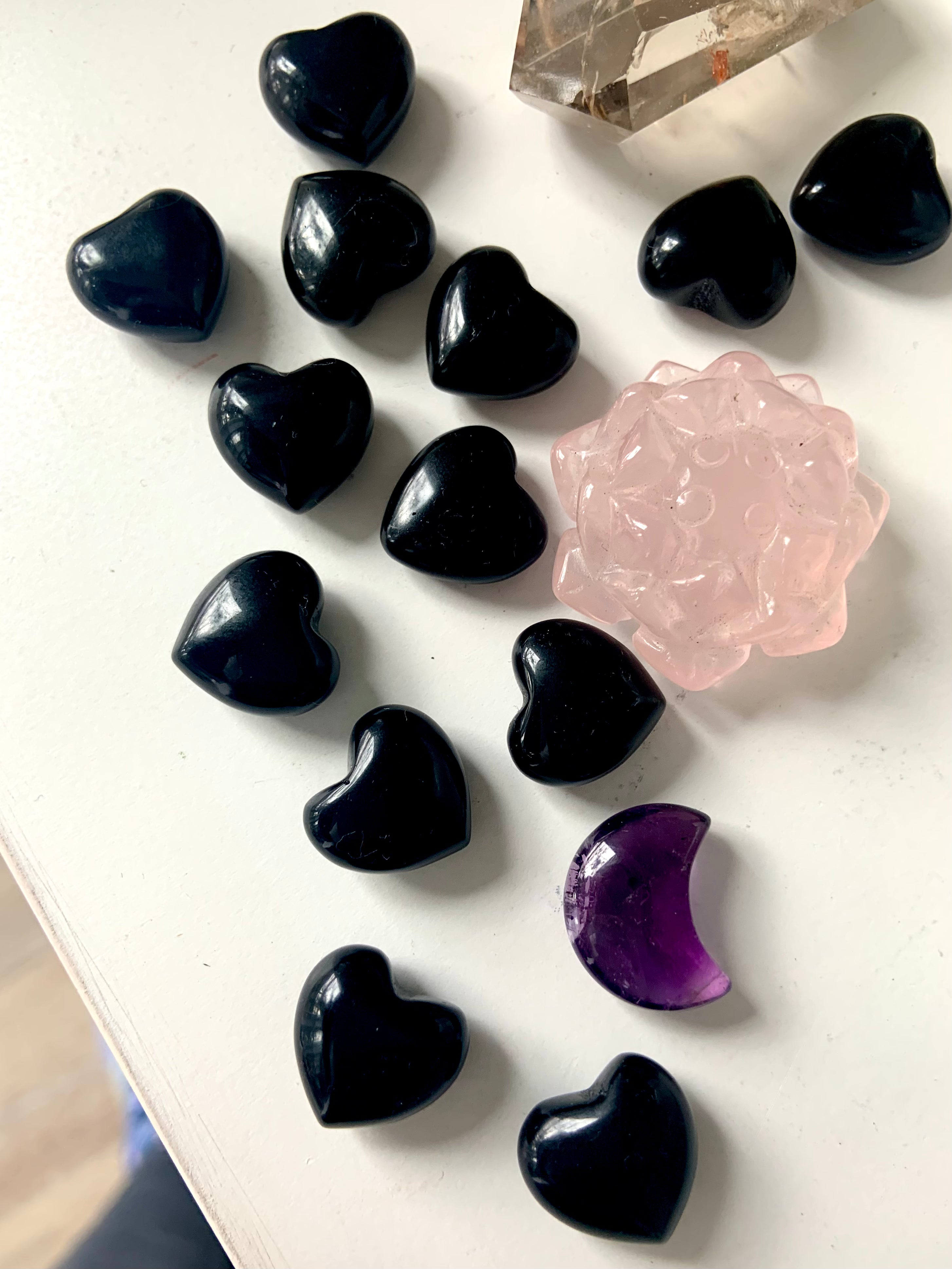 Mini Black Obsidian hearts with polished finish arranged in a flat lay beside a pink rose carving and Amethyst moon for altar inspiration