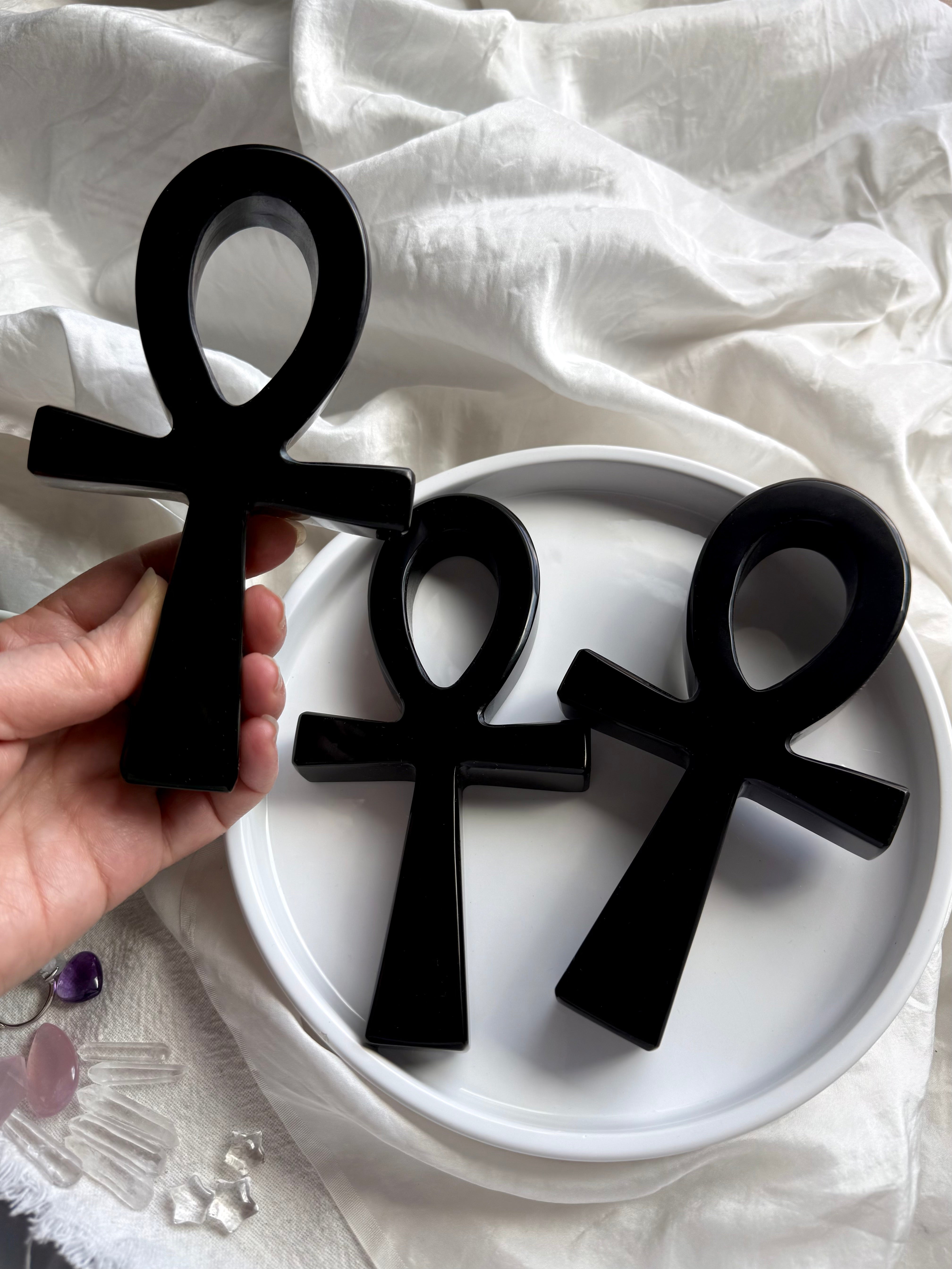 Three black obsidian ankhs displayed together — carved crystal ankhs for spiritual practice and sacred symbolism.