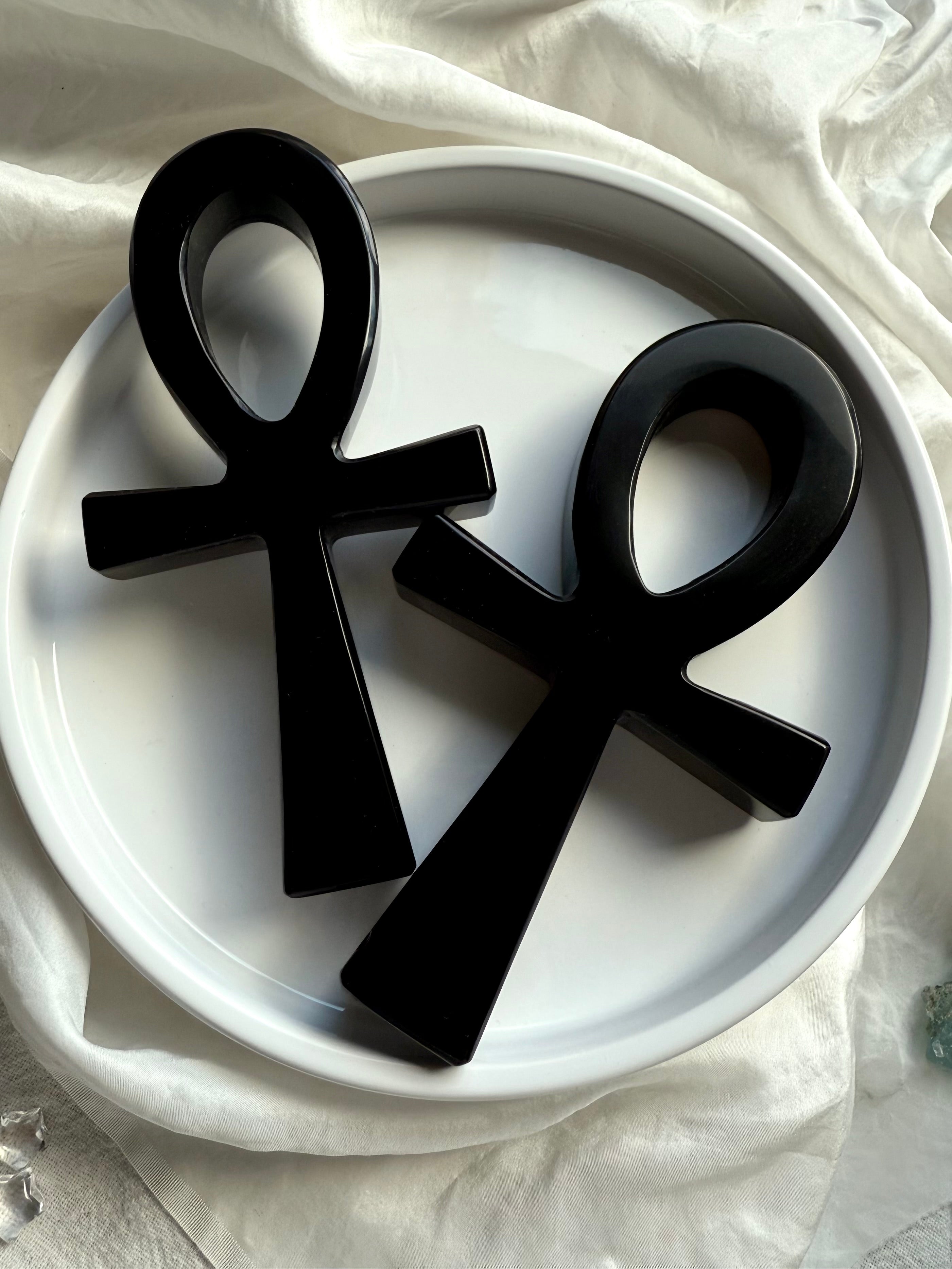 Two polished black obsidian ankh carvings side by side — Egyptian life symbol crystals for chakra alignment and meditation.